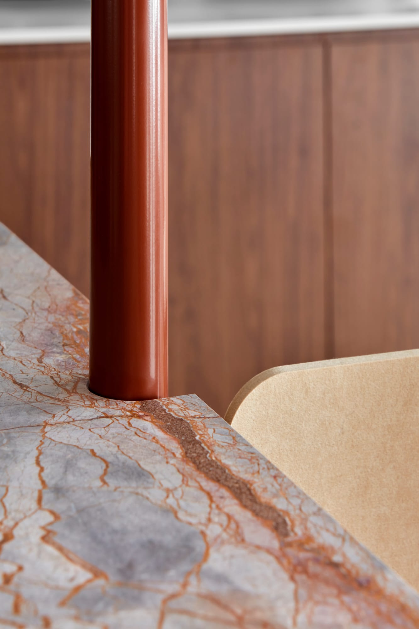 Beacon HQ by Foolscap Studio. Detail shot of cognac colored metal tube connected to gray marble panel.