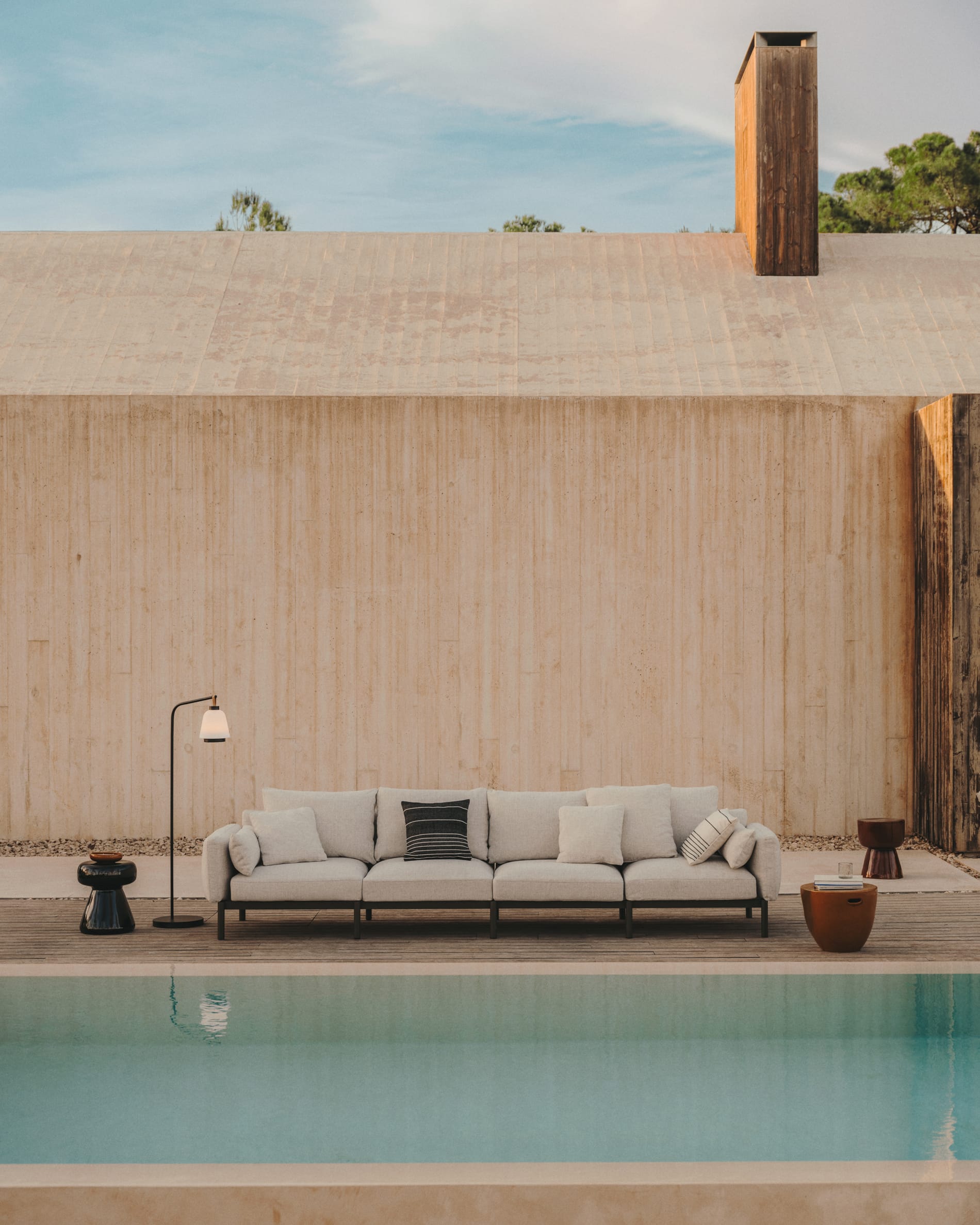 Kave Home. Outdoor sofa at pool with outdoor coffee tables and outdoor floor lamp.