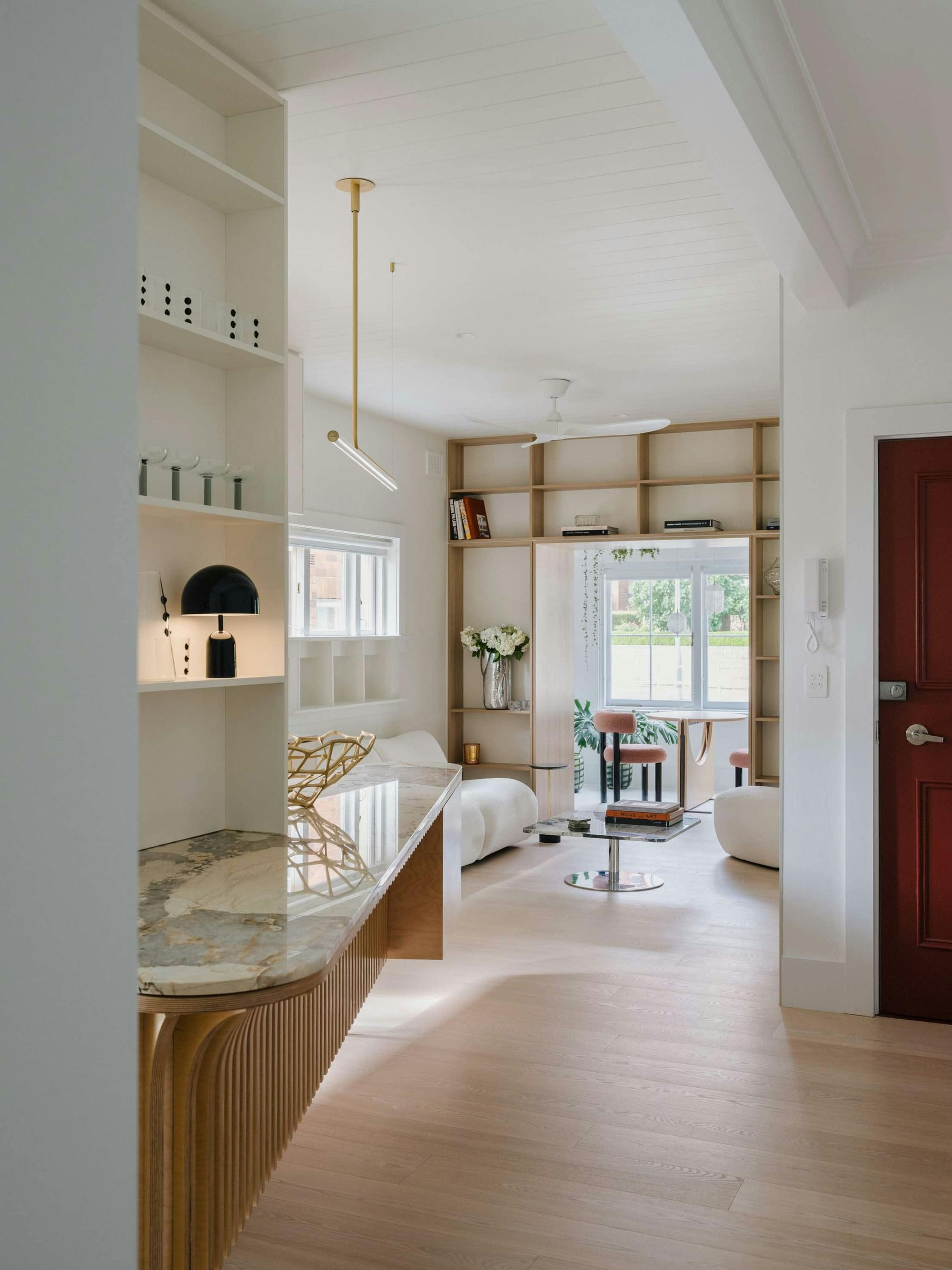 Kirribilli Downsize Apartment by Amandine & Simonetti Architecture. Living room featuring pouf sofa, marble coffee table and wall-width built in shelf.