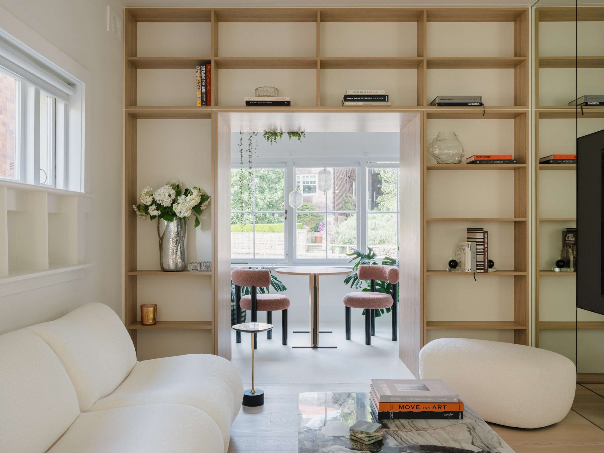 Kirribilli Downsize Apartment by Amandine & Simonetti Architecture. Living room featuring pouf sofa, marble coffee table and wall-width built in shelf.