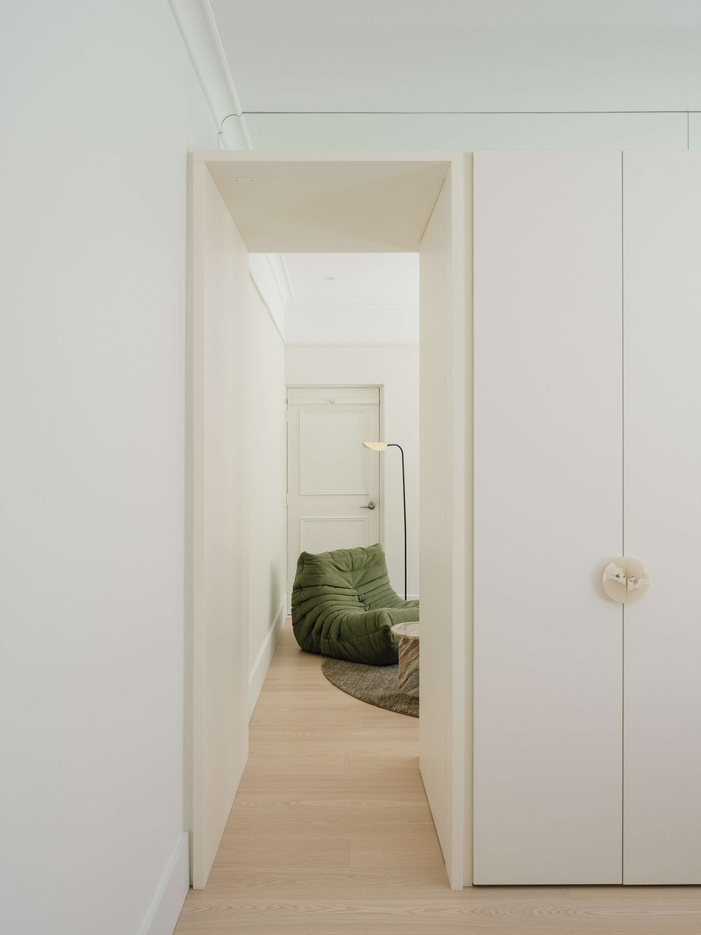 Kirribilli Downsize Apartment by Amandine & Simonetti Architecture. Green 'lazy caterpillar lounge chair' by Michel Ducaroy and built-in cabinet.