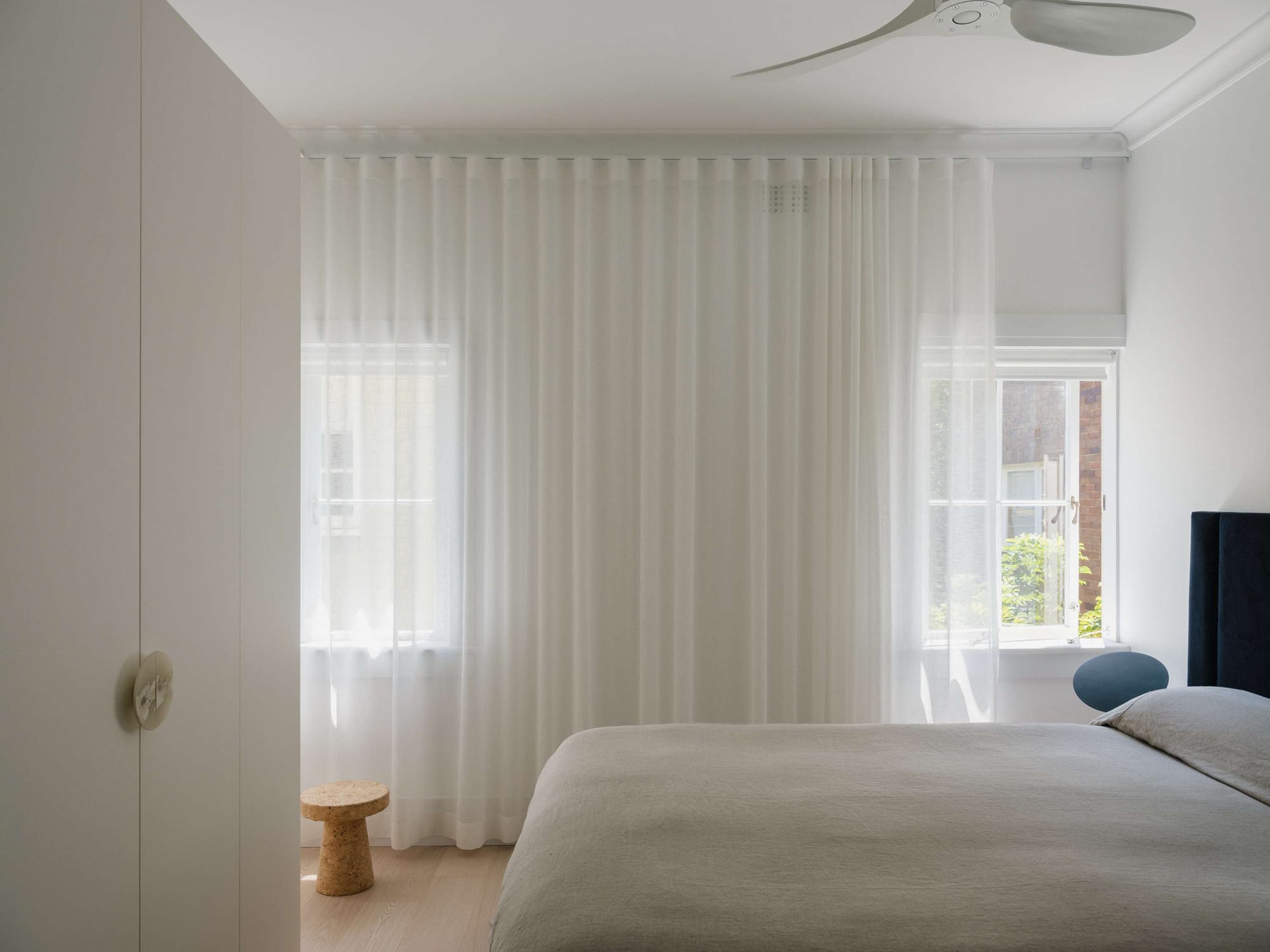 Kirribilli Downsize Apartment by Amandine & Simonetti Architecture. Bedroom view with built-in cabinet and floor to ceiling curtains.