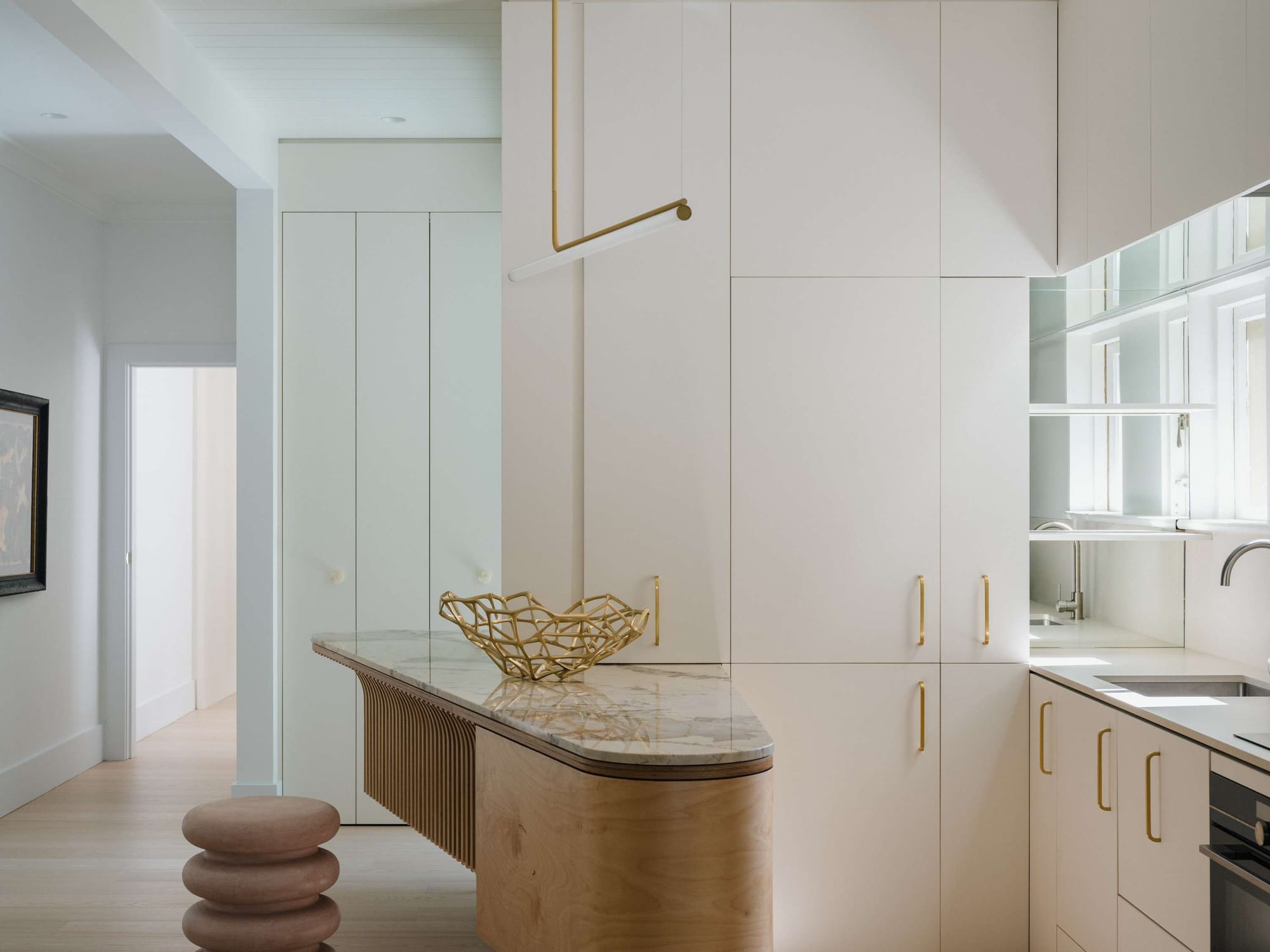 Kirribilli Downsize Apartment by Amandine & Simonetti Architecture. White kitchen, costumised marble and plywood island.