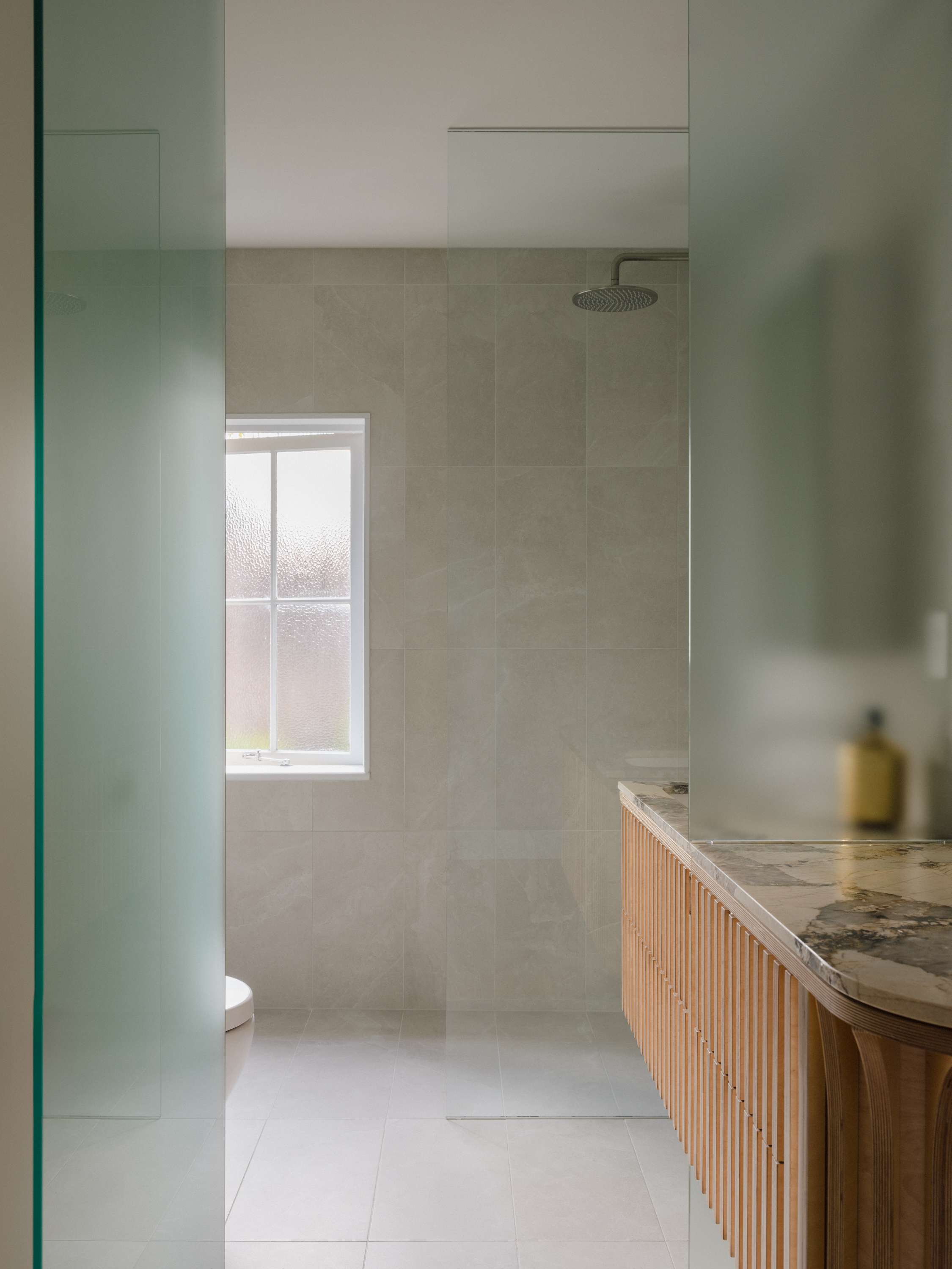 Kirribilli Downsize Apartment by Amandine & Simonetti Architecture. Customised counter with marble work top and floor to ceiling sandblasted glass door.