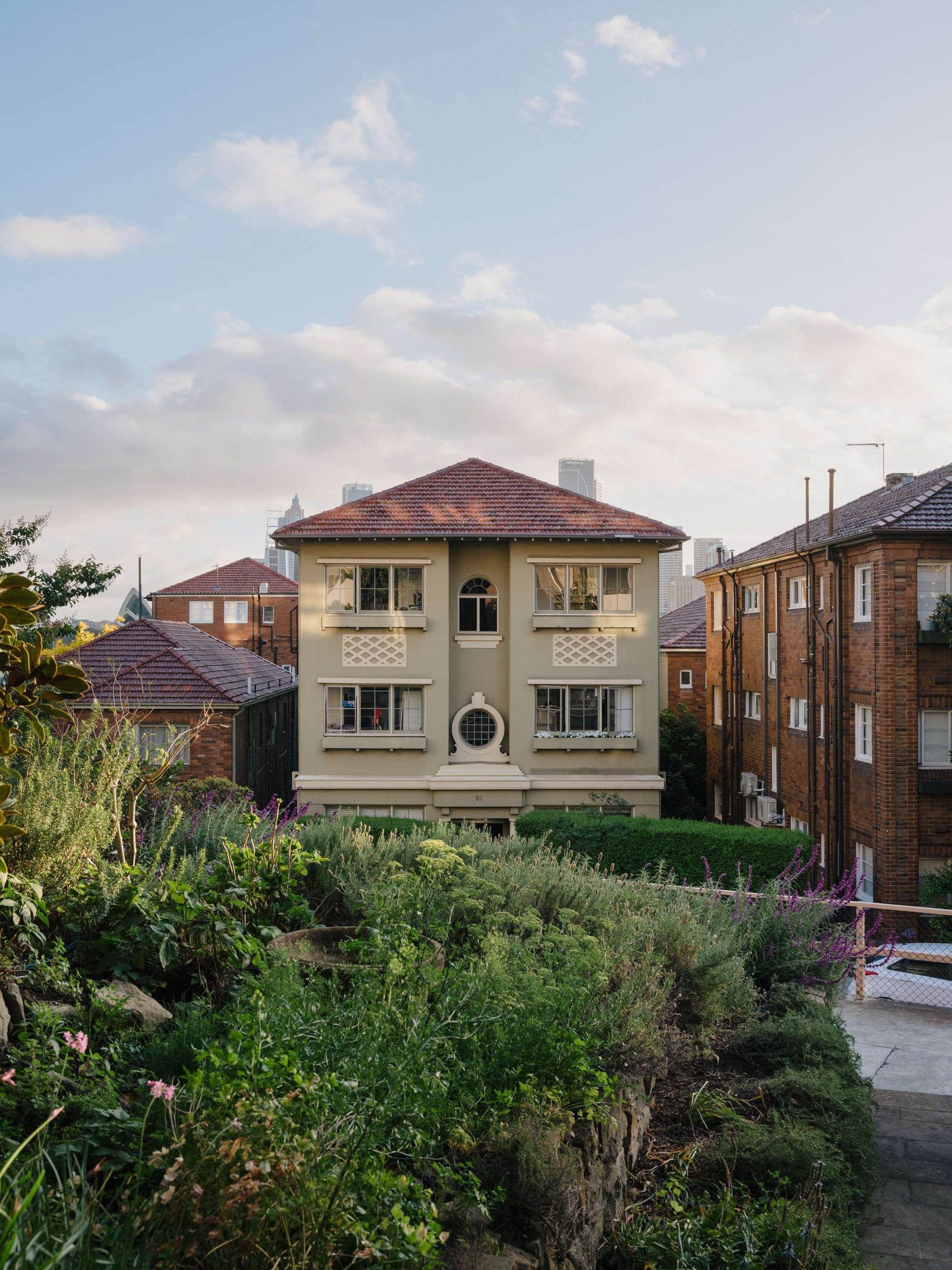 Kirribilli Downsize Apartment by Amandine & Simonetti Architecture. Townhouse view with garden and skyscrapers in the background.