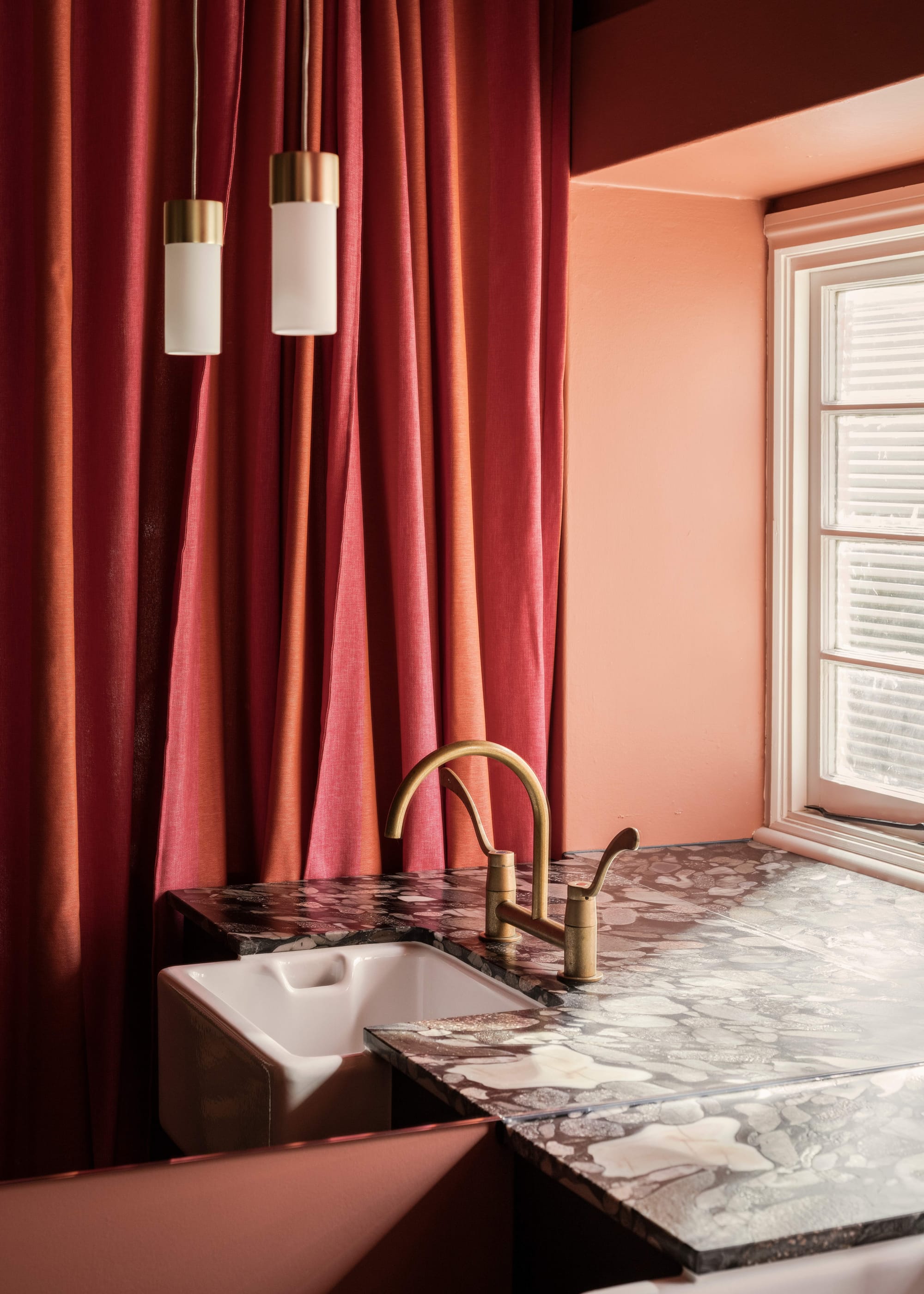 An interior detail shot showing a red marble basin with a red curtin in the background