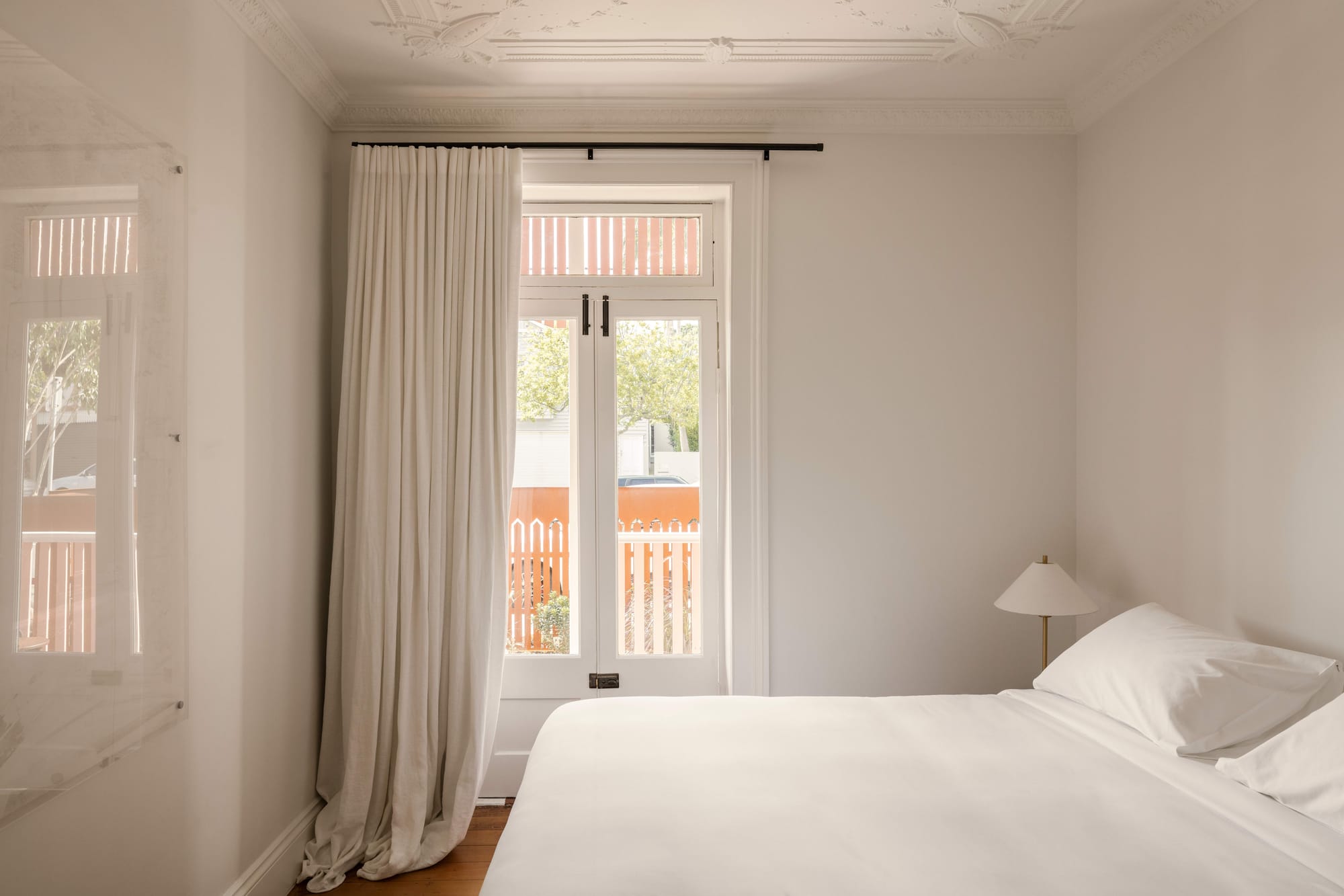 An interior shot of Miss Midgleys showing the white bedroom with a door out to a balcony