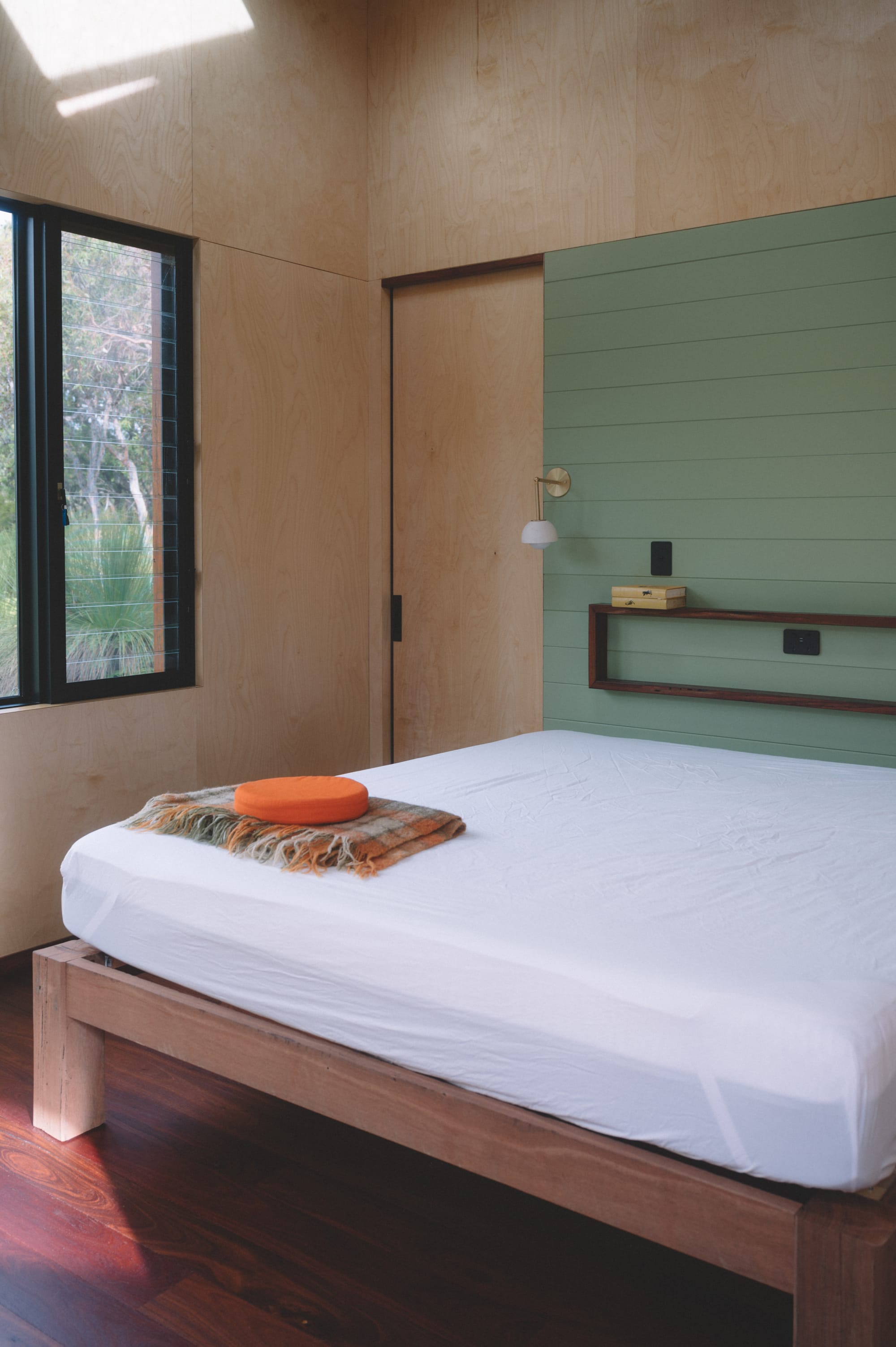 Nullaki House by Bare Architects. Bedroom view featuring minimalistic interior with plywood and wasabi green walls.