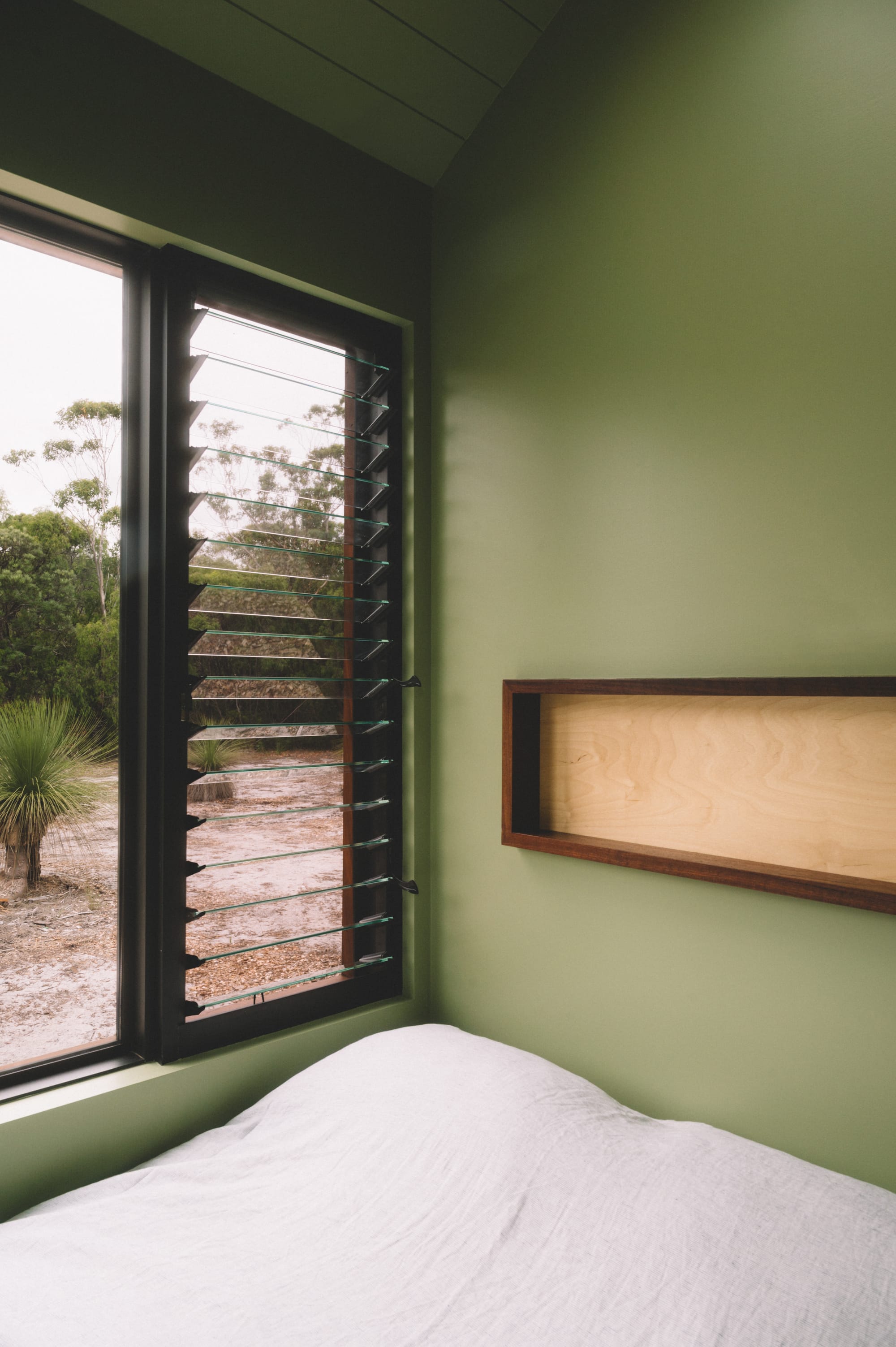 Nullaki House by Bare Architects. Bedroom interior featuring green walls and view to nature.