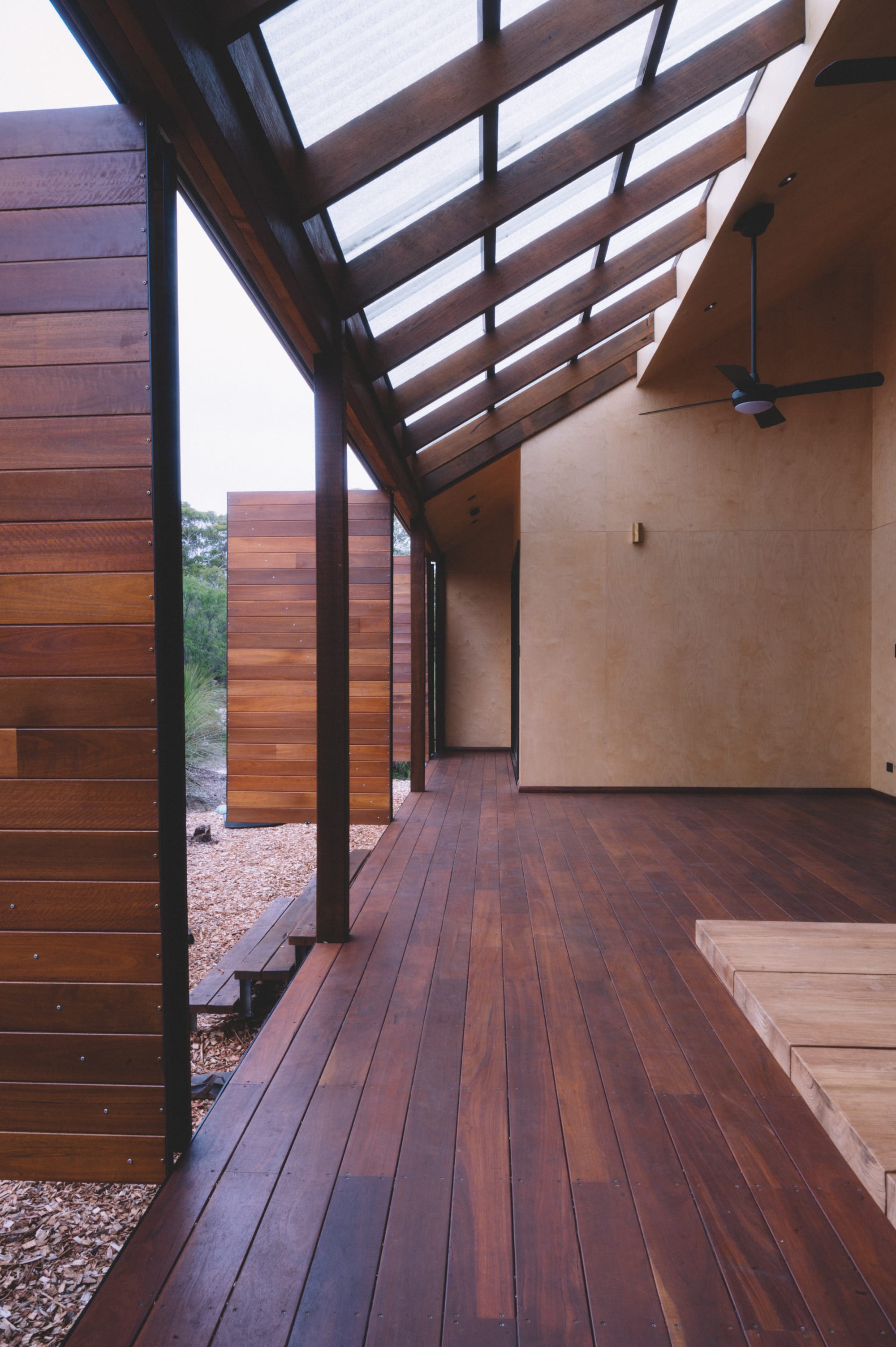 Nullaki House by Bare Architects. Wood panel terrace with bifold doors and plywood walls and view to nature.