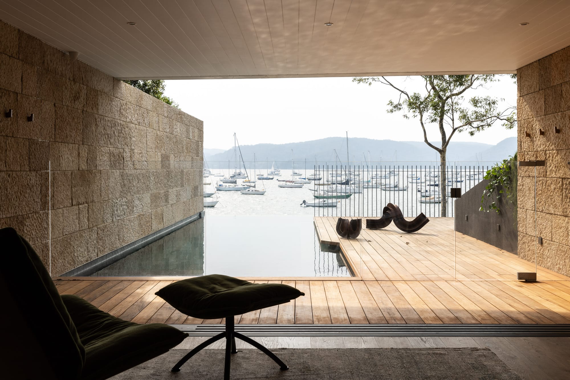 Ripple House by Marker Architecture. Wooden staircase featuring modern house with sandstone wall and concrete balcony.