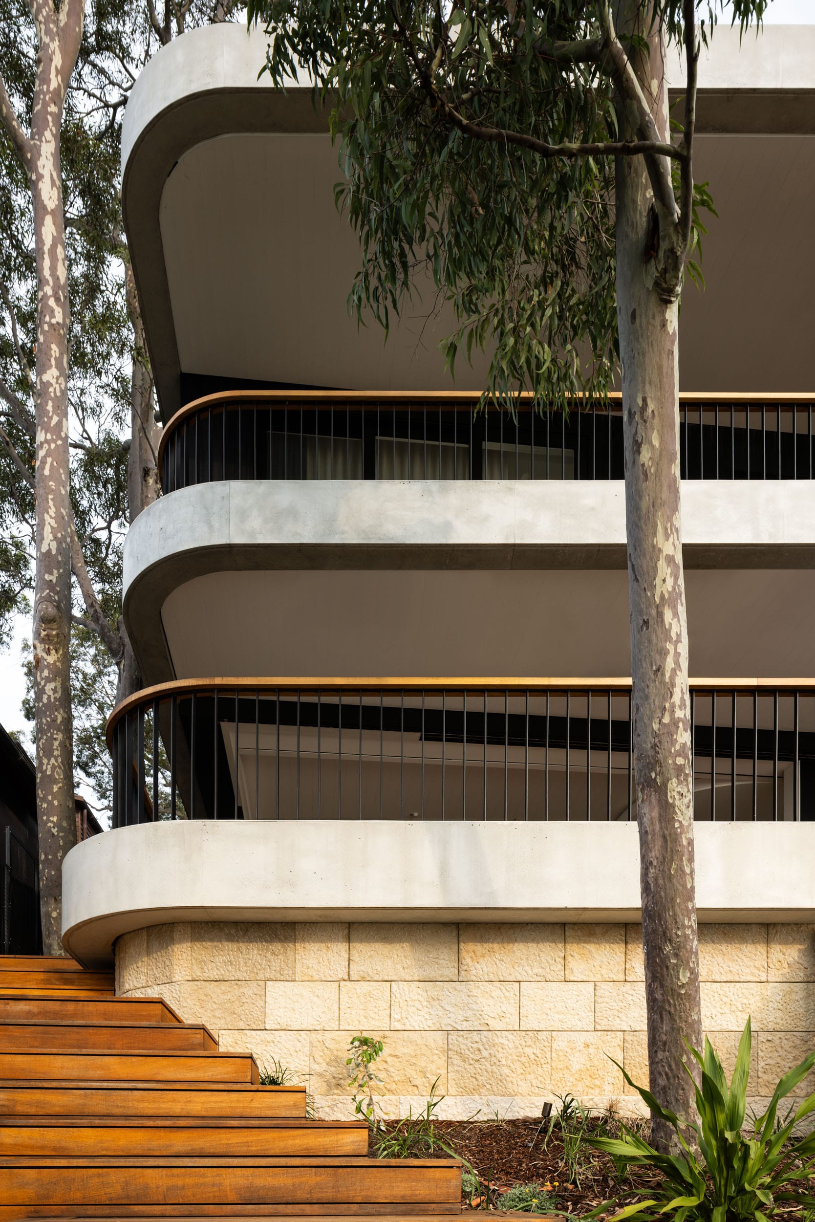 Ripple House by Marker Architecture. Exterior view on modern house with balconies, wooden staircase concrete flooring and sandstone wall.