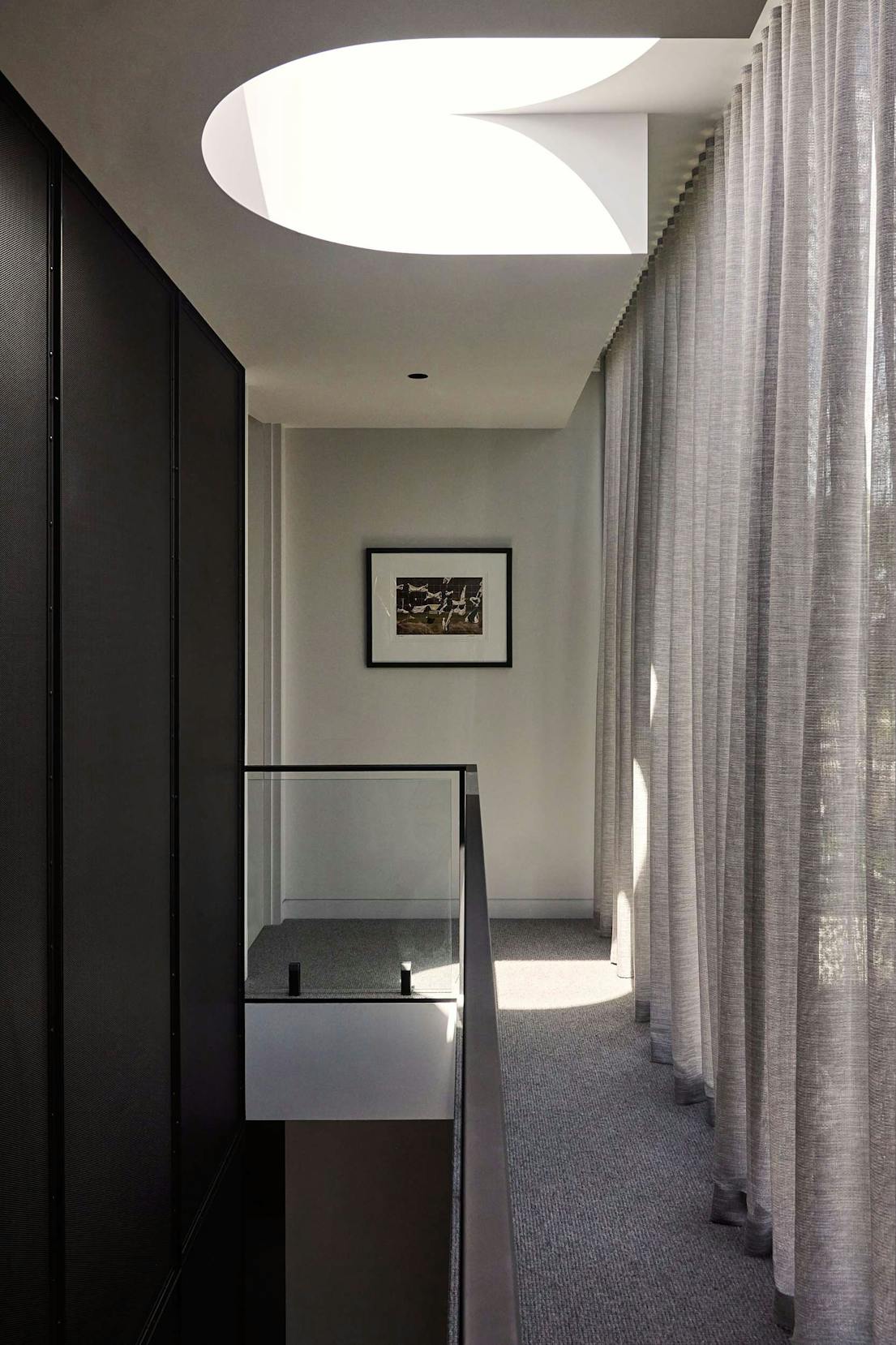 The Bach Pad by Merrylees Architects. Elegant, minimalistic hallway with ceiling window and grey floor to ceiling curtains.