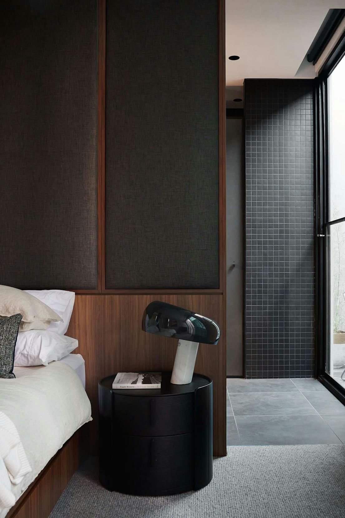 The Bach Pad by Merrylees Architects. Bedroom featuring dark wooden fitted cabinets, side table and black snoopy table lamp.