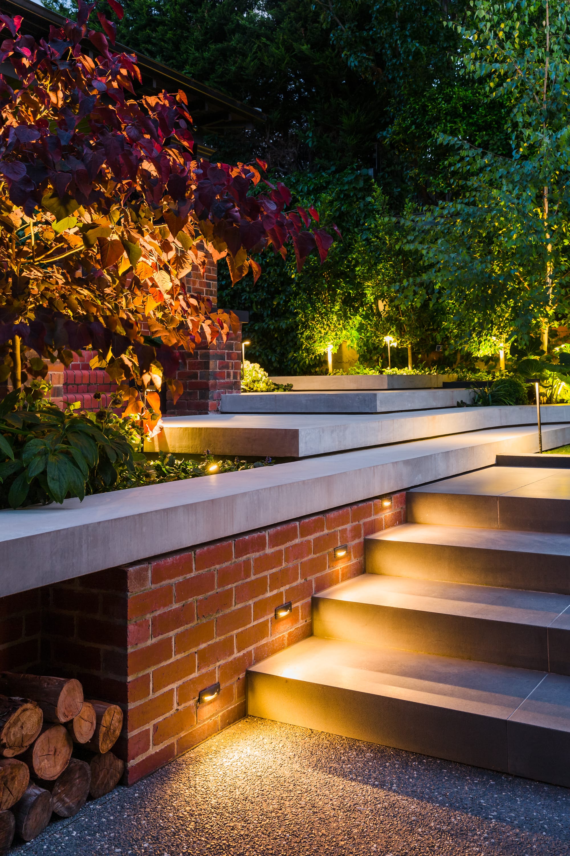 View to green garden showing a rendered retaining wall with green plants.