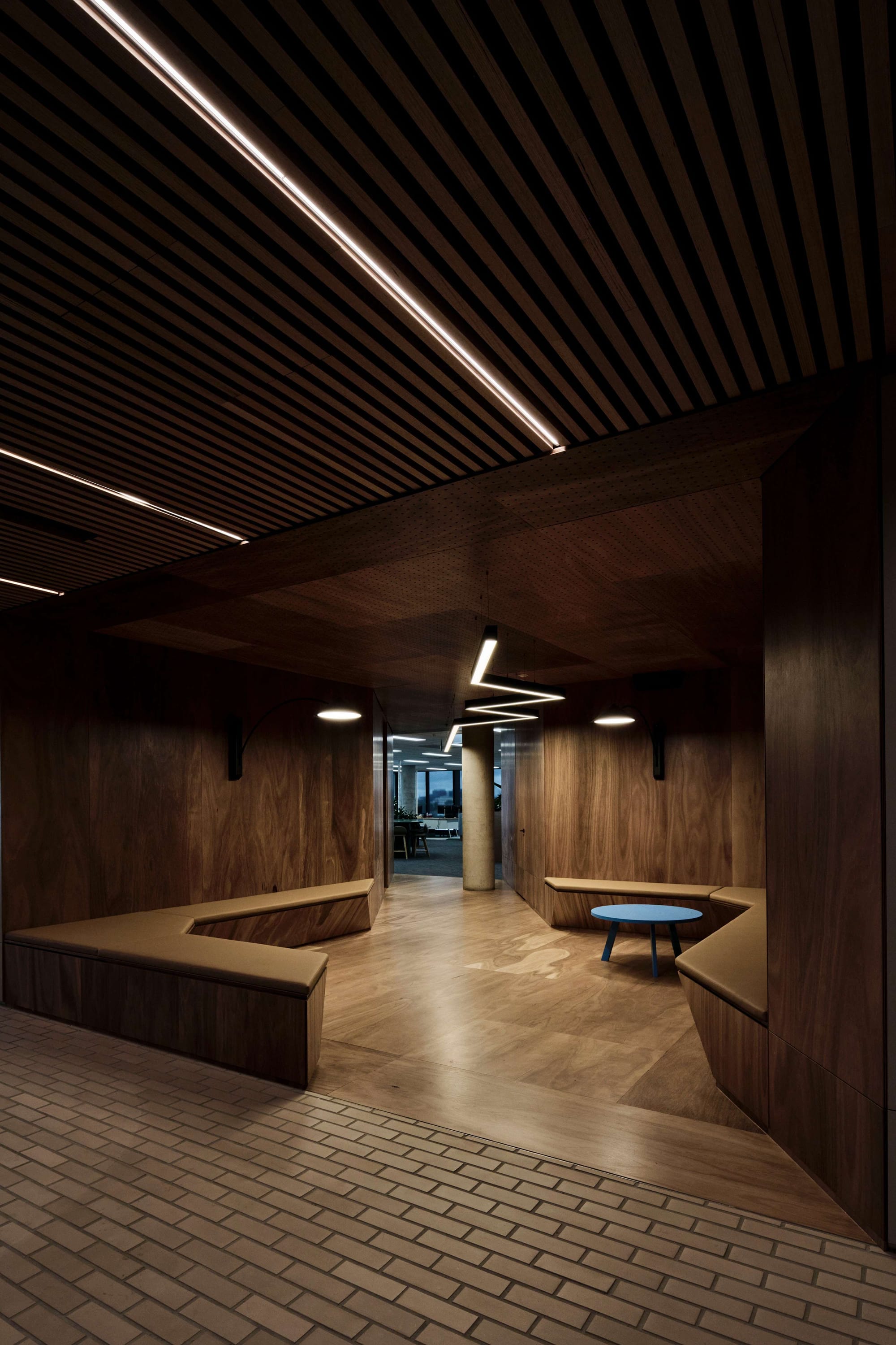 Icon HQ by FIGR. Wooden covered office open lounge area featuring bespoke seating area snd perforated ceiling.