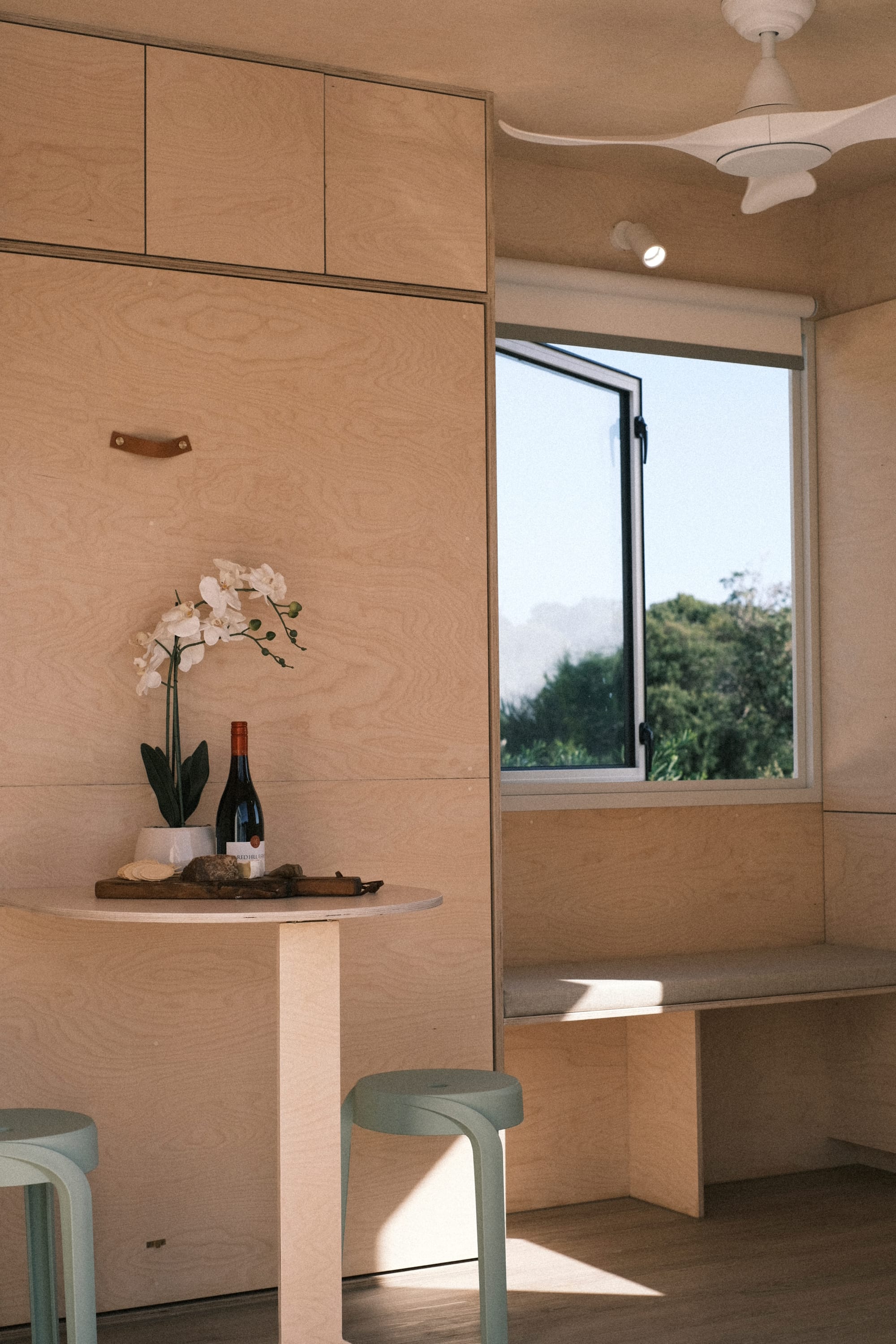 Flower and Ward by Base Cabin. Minimalistic, tiny home interior featuring plywood walls and ceiling and window to nature.