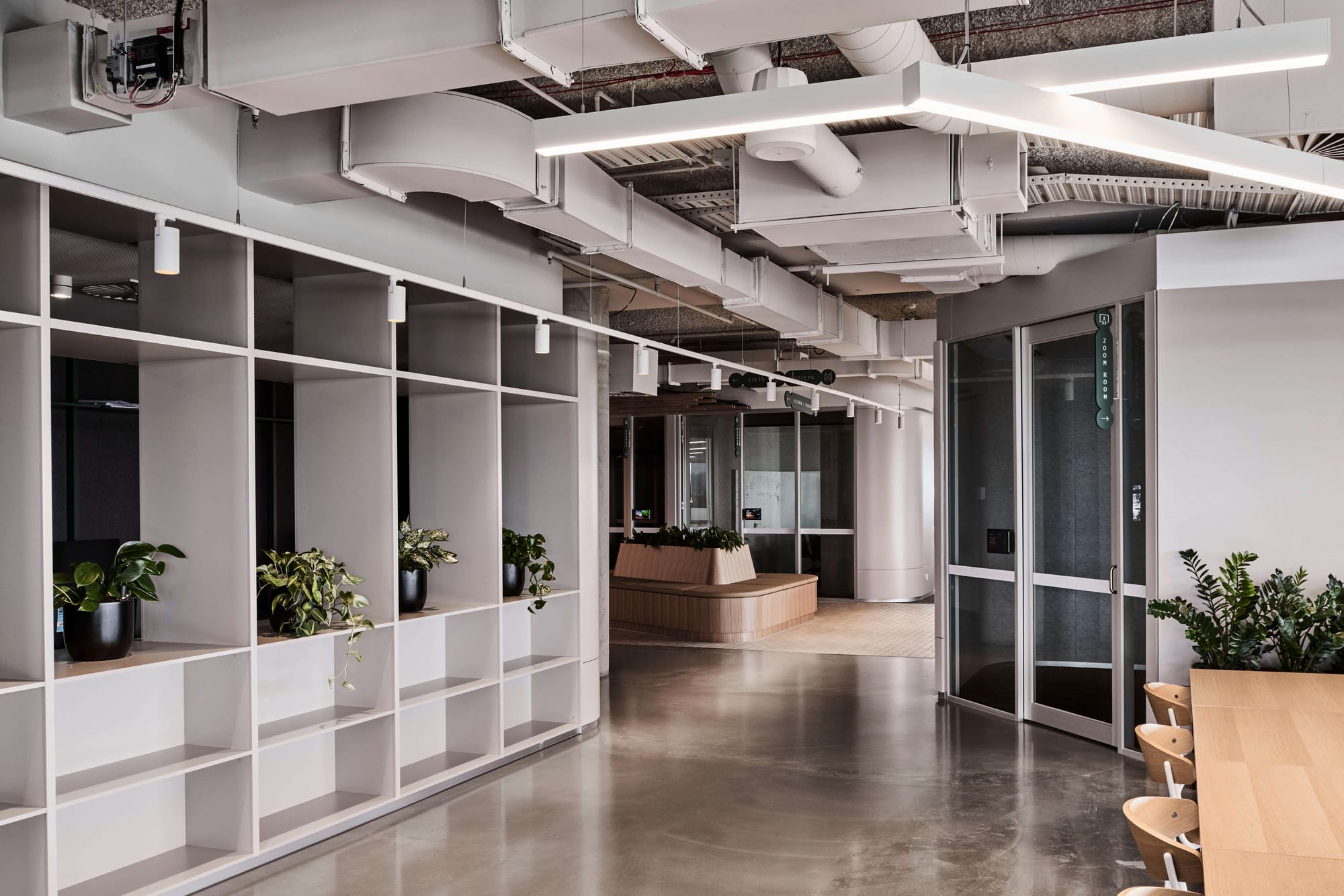 Icon HQ by FIGR. Office corridor featuring white industrial ceiling, fitted shelves and floating screed.