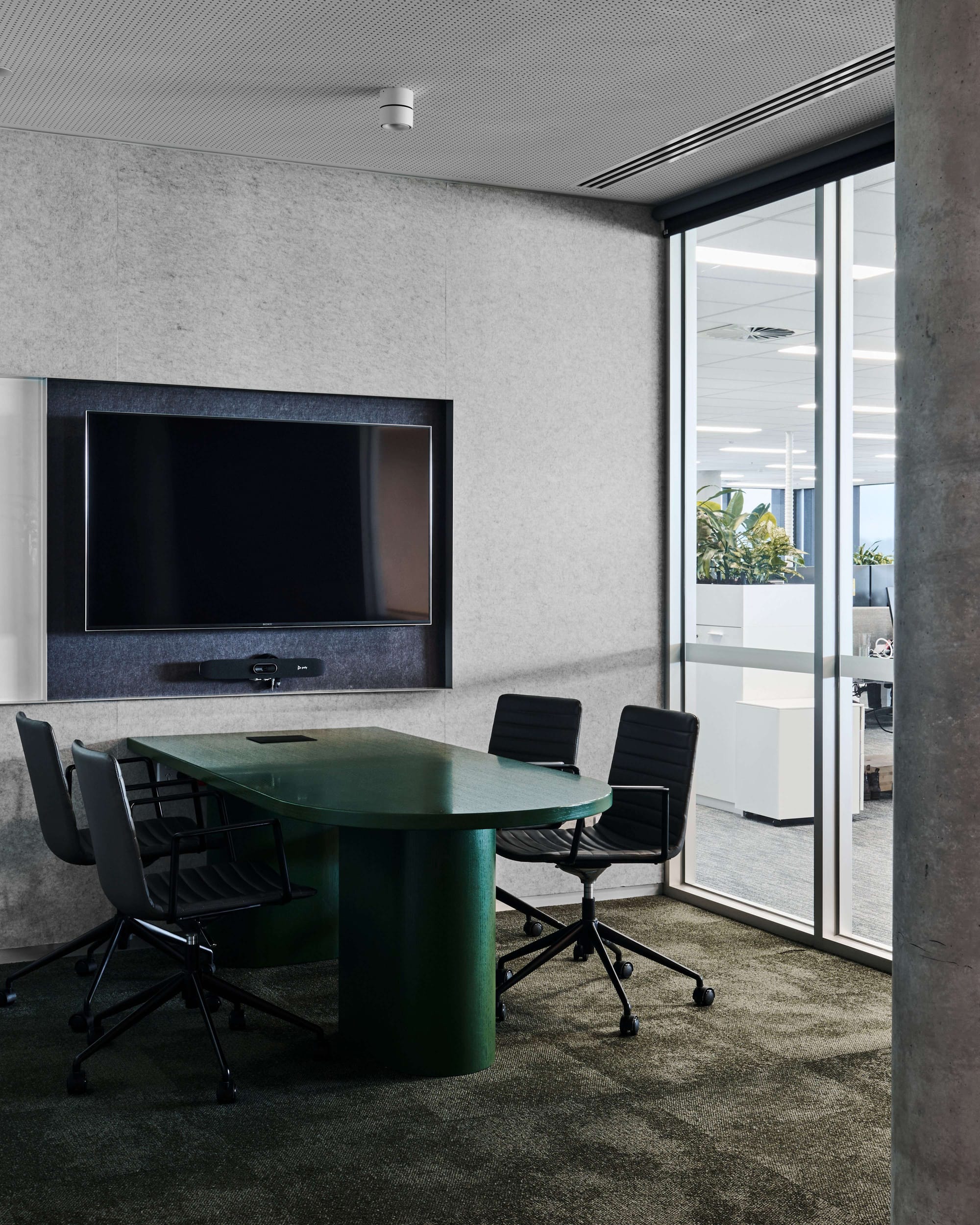 Icon HQ by FIGR. Office meeting room featuring rounded, wooden, green varnished table, vitra office chairs and glass sliding door.