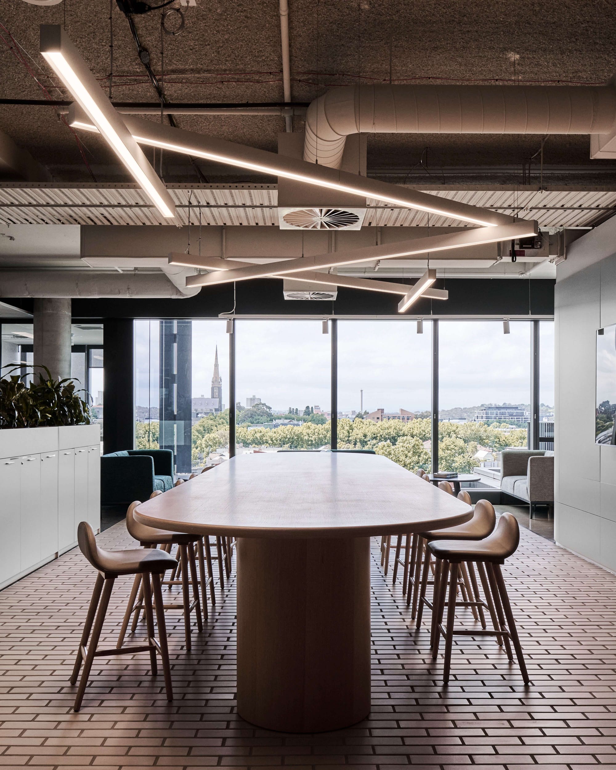 Icon HQ by FIGR. Office common area featuring wooden seating group and floor to ceiling windows with view on nature.