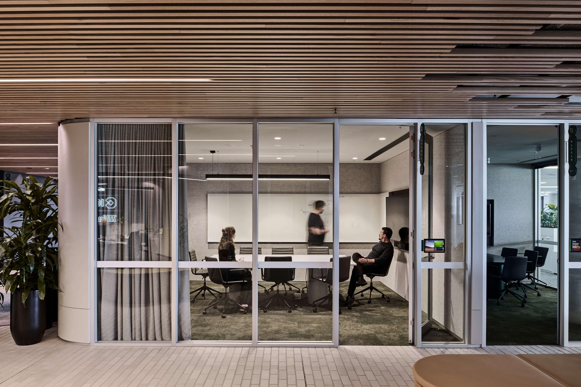 Icon HQ by FIGR. Glassed office meeting room featuring green carpet and perforated acoustic ceiling.