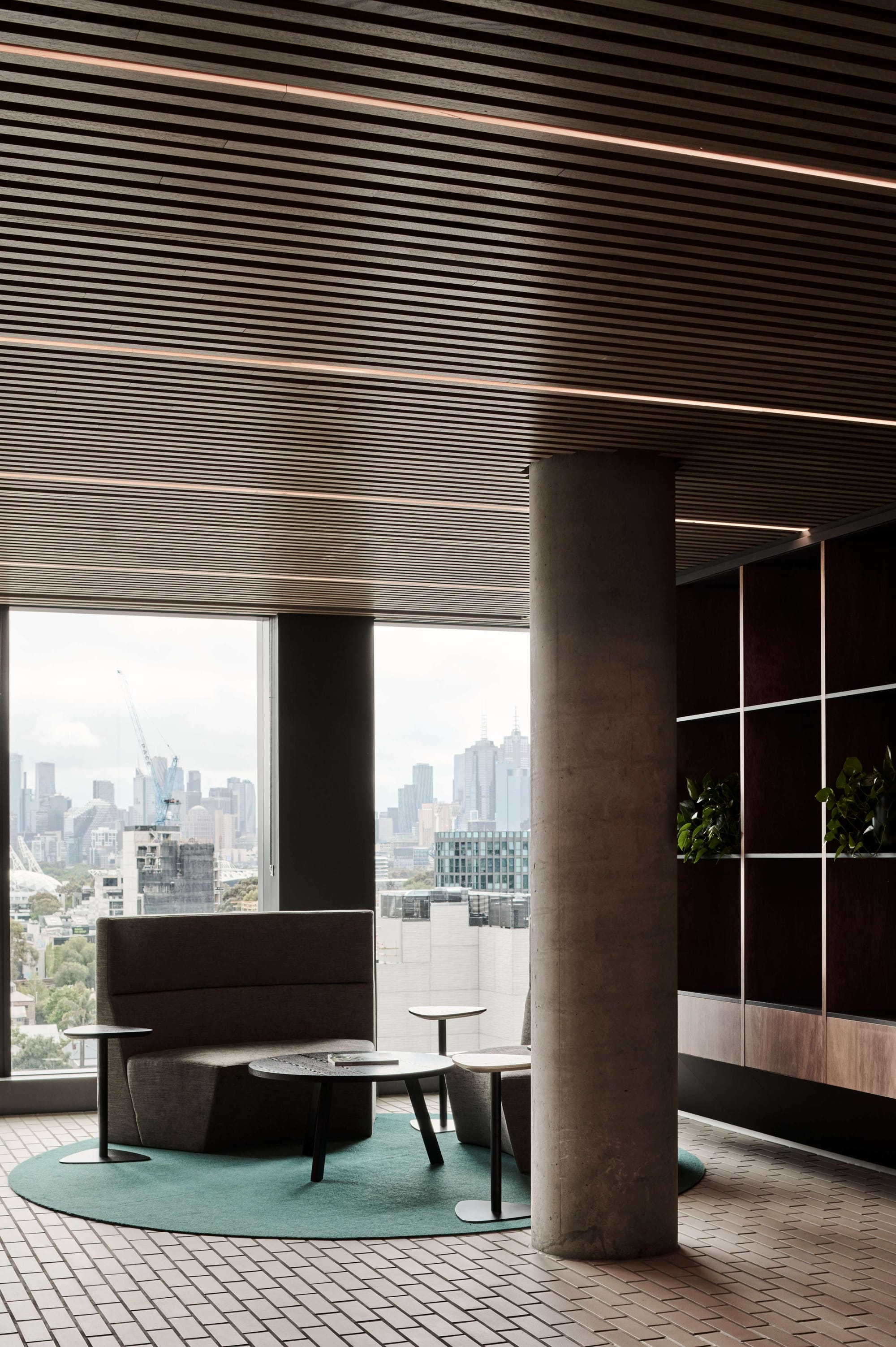 Icon HQ by FIGR. Office lounge area featuring grey sofas and floor to ceiling windows with view on city.