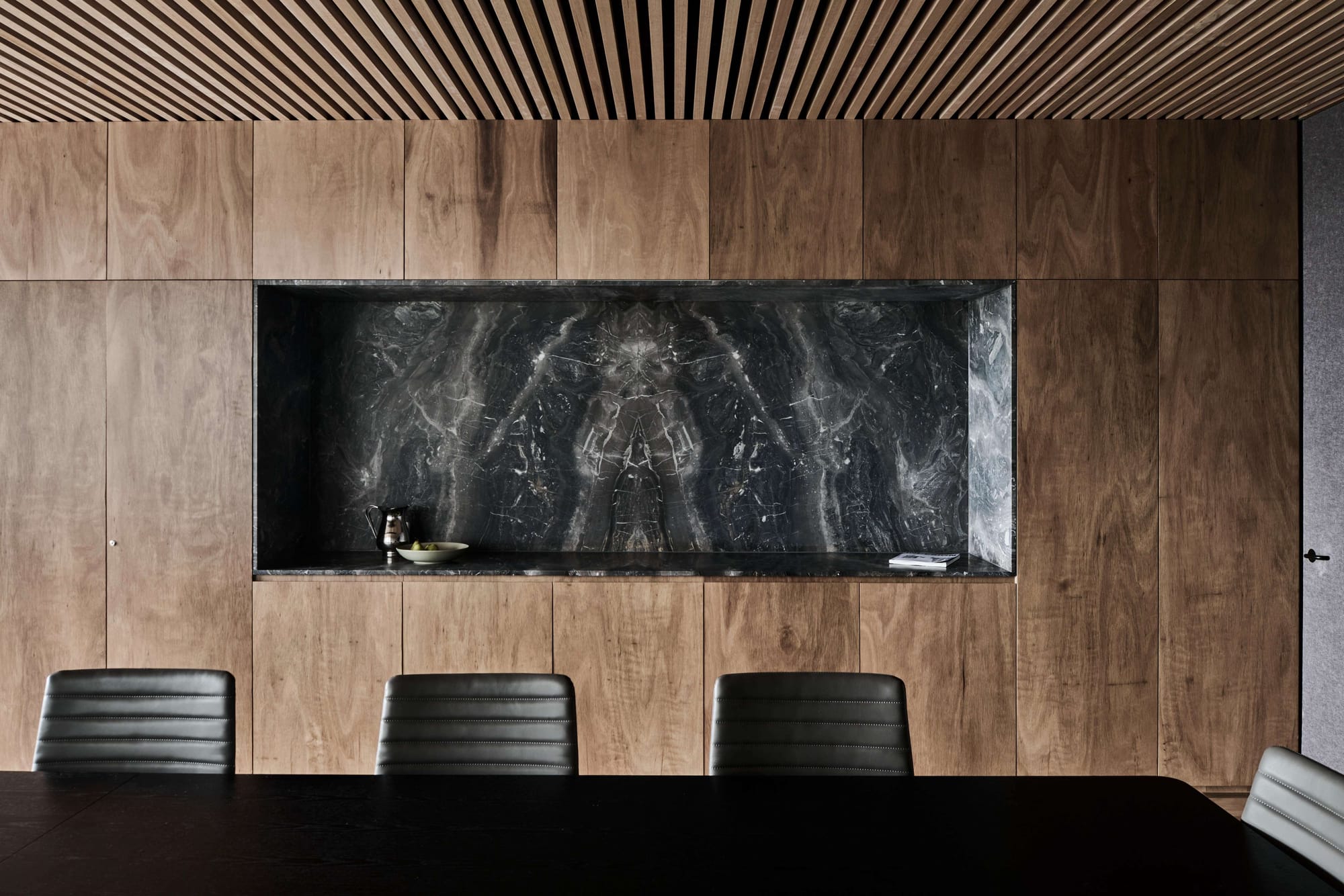 Icon HQ by FIGR. Detail shot of office conference room featuring black table and black marble wall niche.