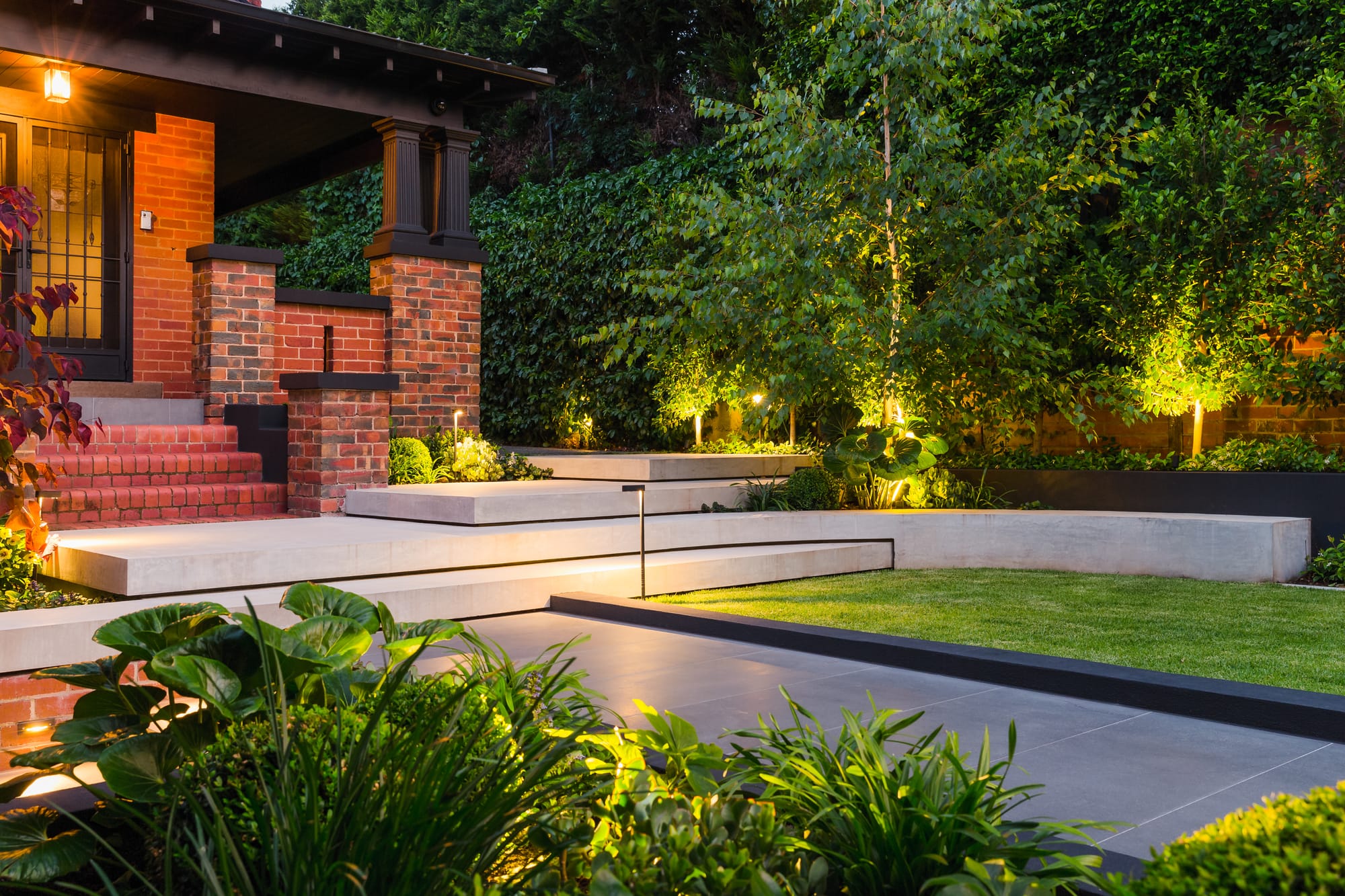 View to illuminated green garden and brick house.