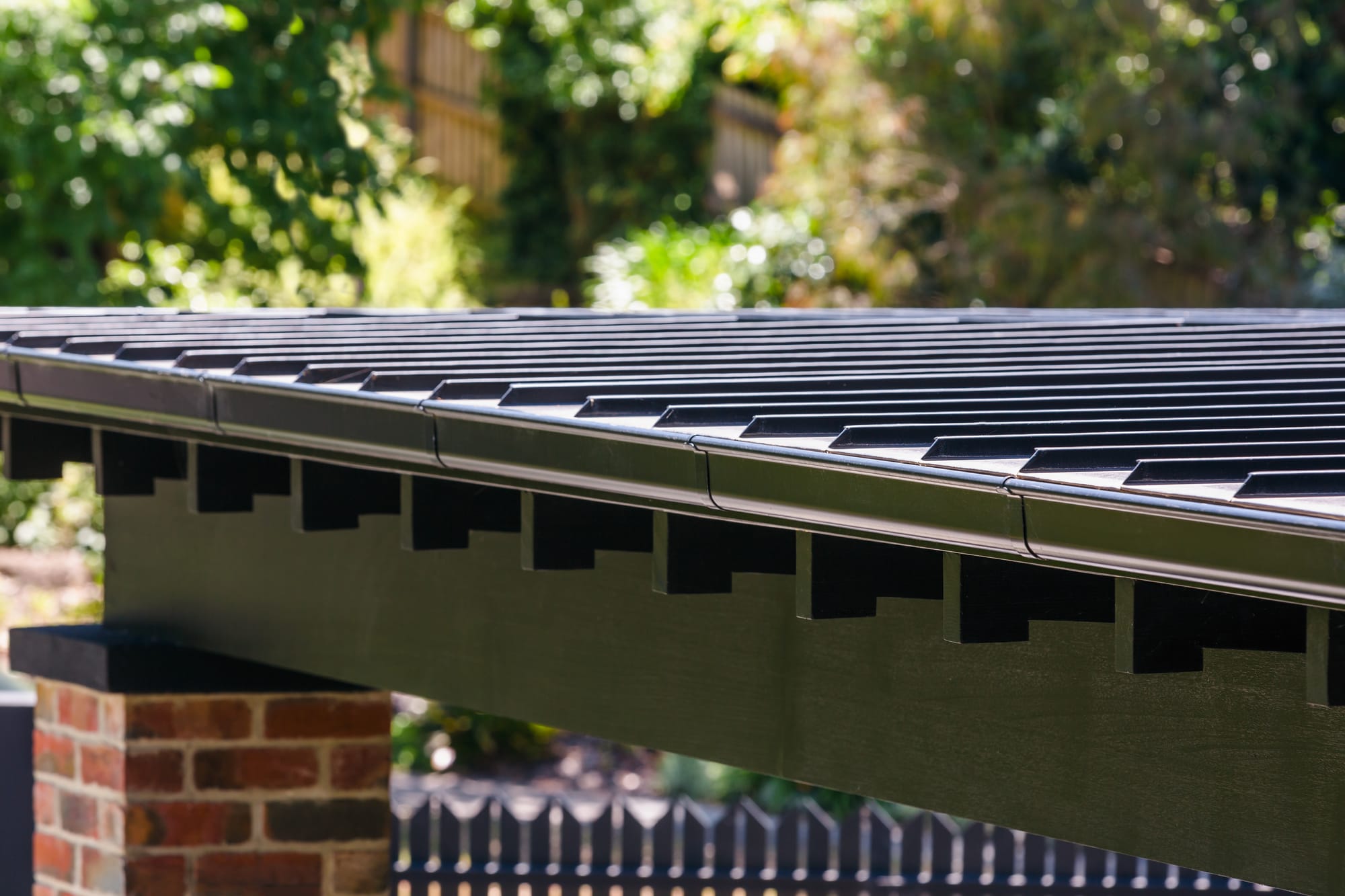 Low sloping gabled roof overhang detail mounted on brick brace.