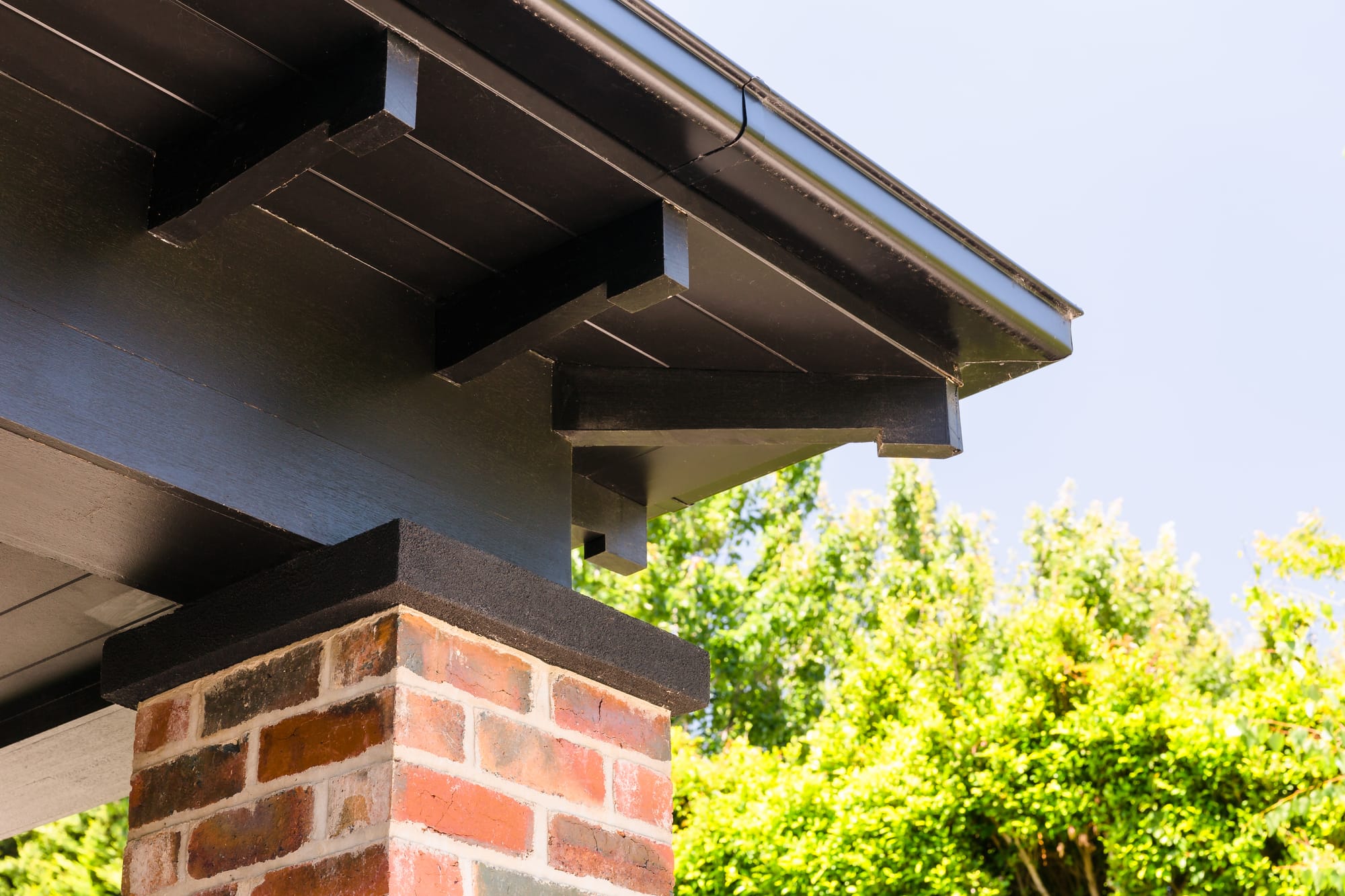 Low sloping gabled roof overhang detail mounted on brick brace.