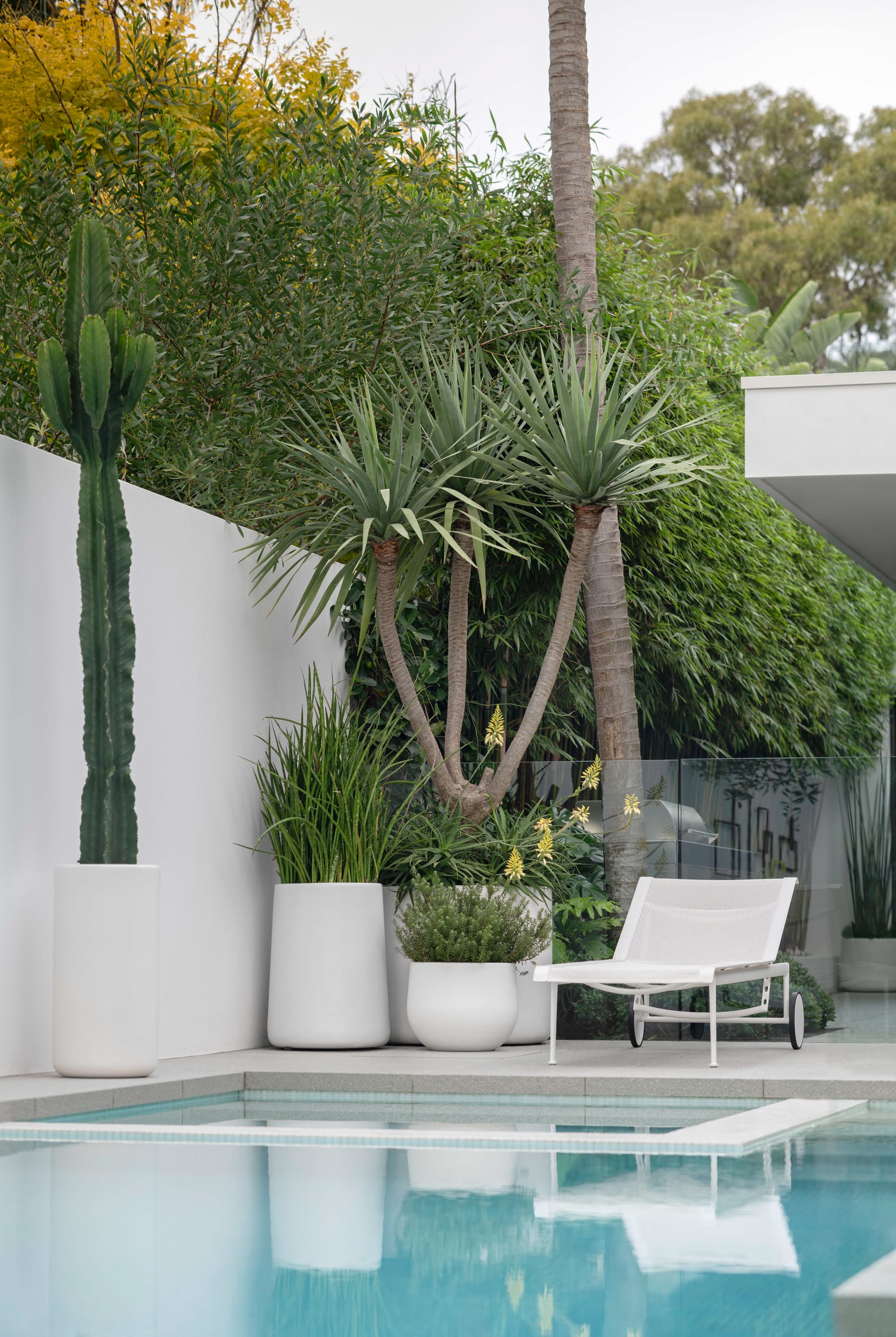 Outdoor Collection by Hibernate. View to pool featuring handcrafted, lightweight, white, high-quality marine-grade fiberglass plant pots.