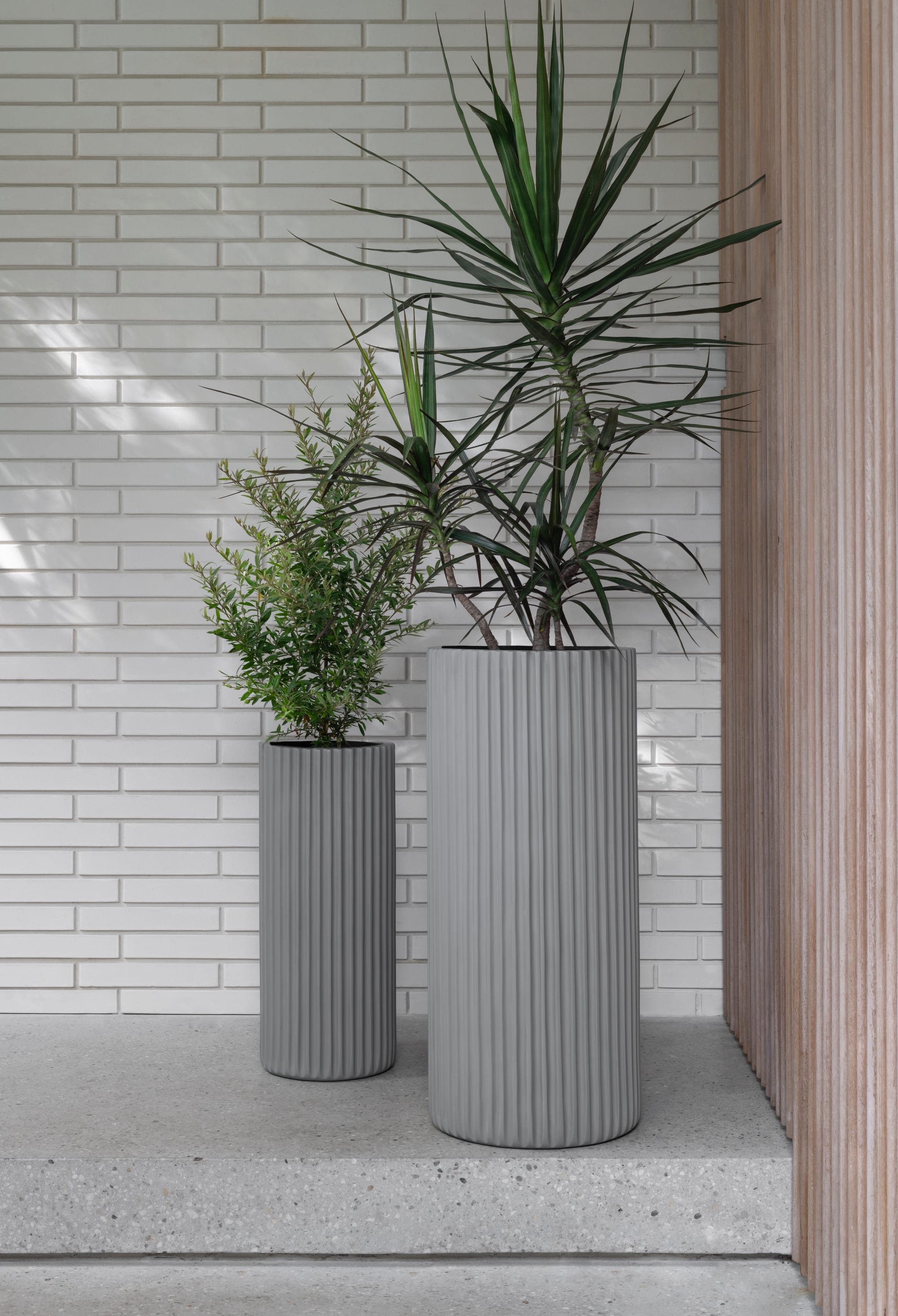 Outdoor Collection by Hibernate. Handcrafted, lightweight, light grey, high-quality marine-grade fiberglass tubular, textured plant pots.