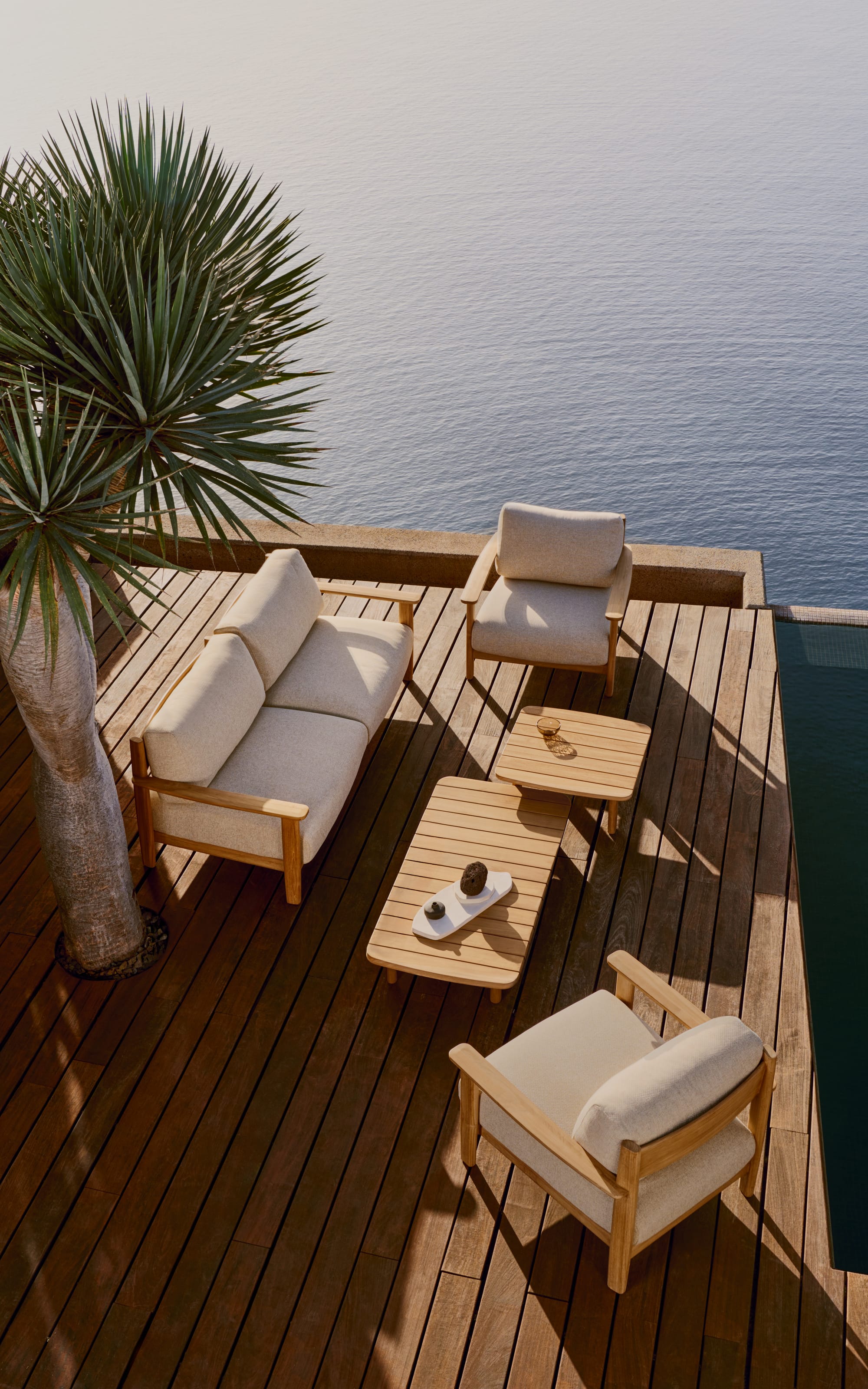 Tirant by Kave Home. Teak wood outdoor collection featuring sofa, armchair and coffee table on terrace with pool and ocean view.