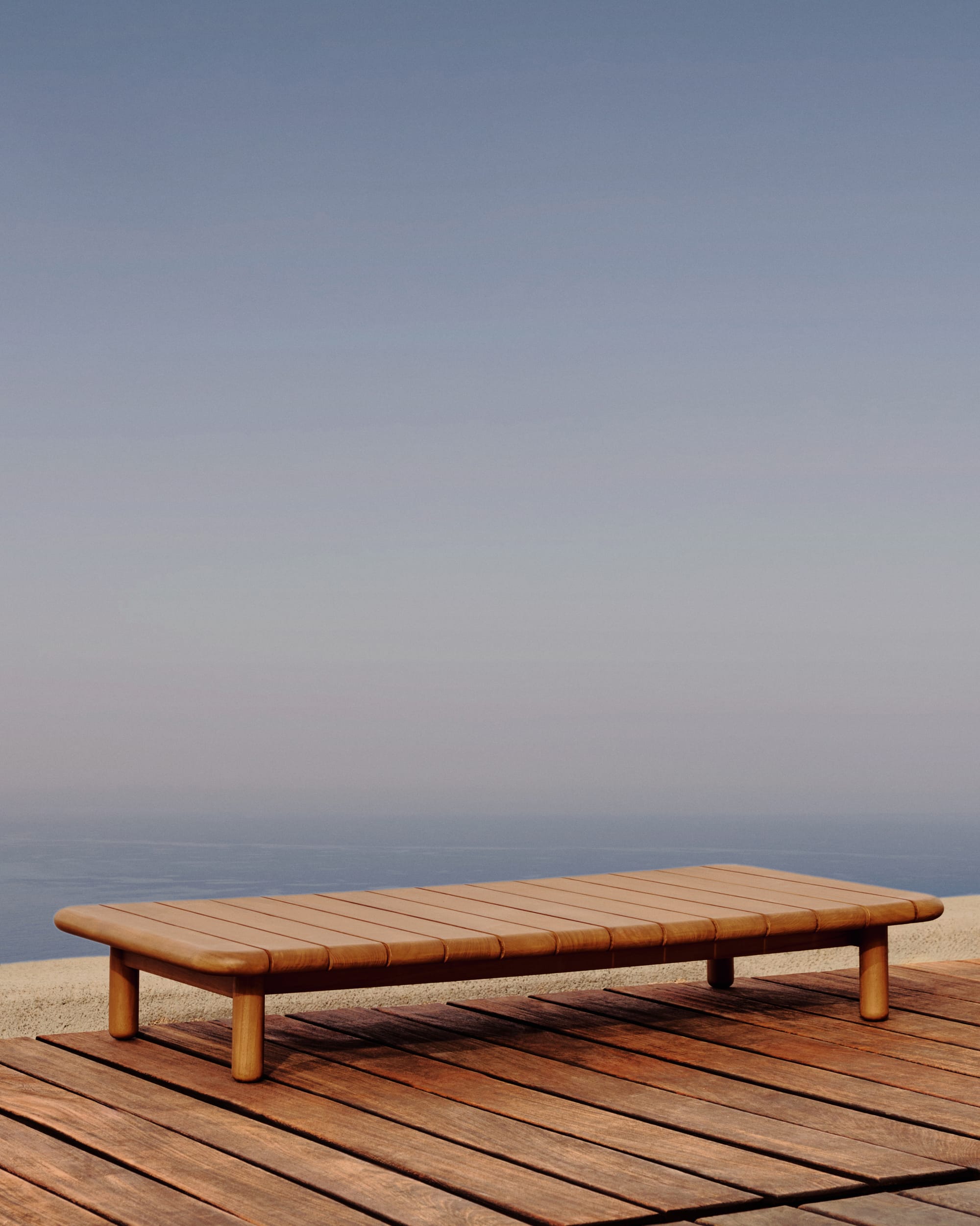 Turquetta by Kave Home. Curved teak wood outdoor coffee table on Mediterranean terrace with ocean view.