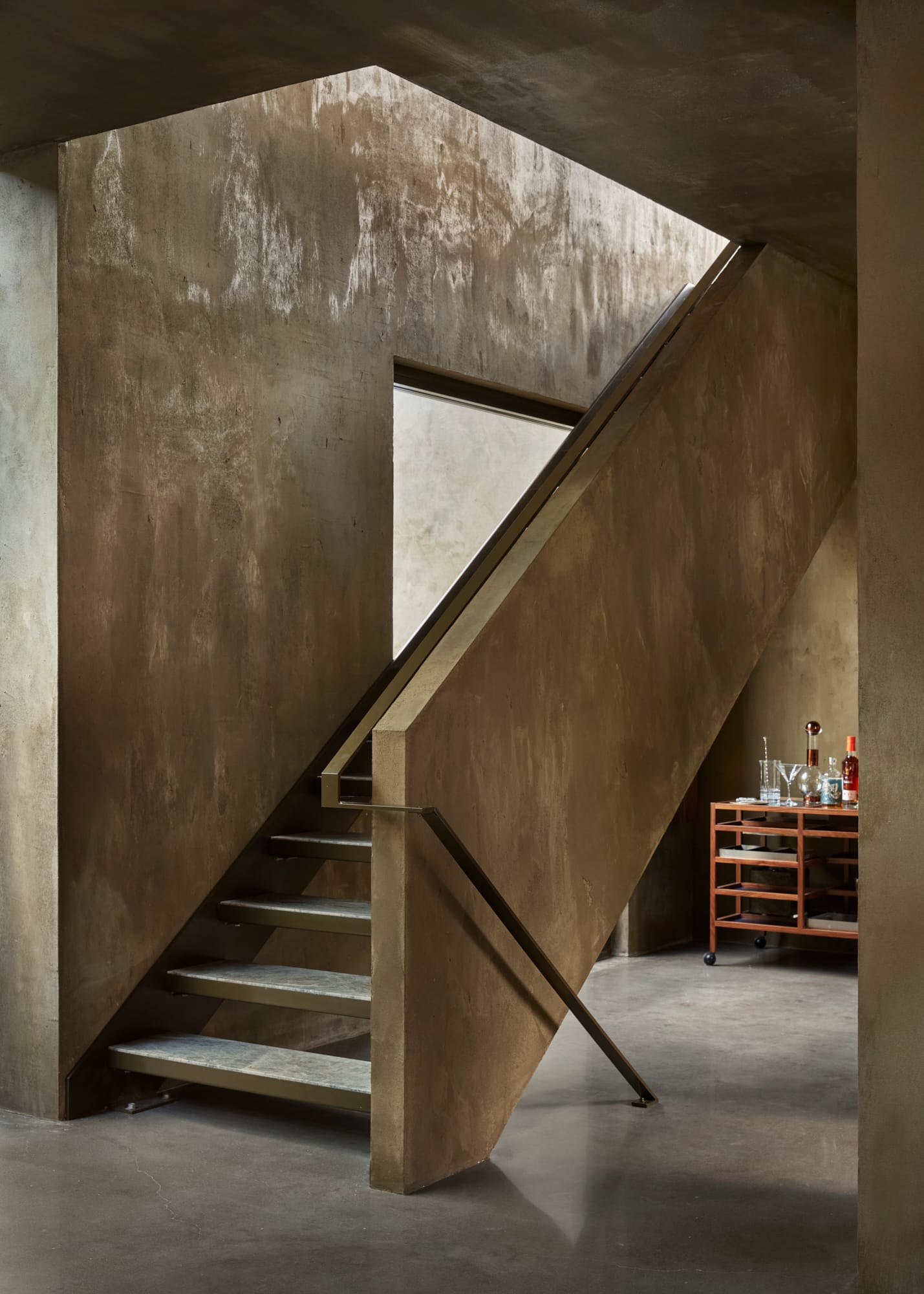 Proclamation House by State of Kin. Hempcrete indoor staircase featuring flatted brass railing.