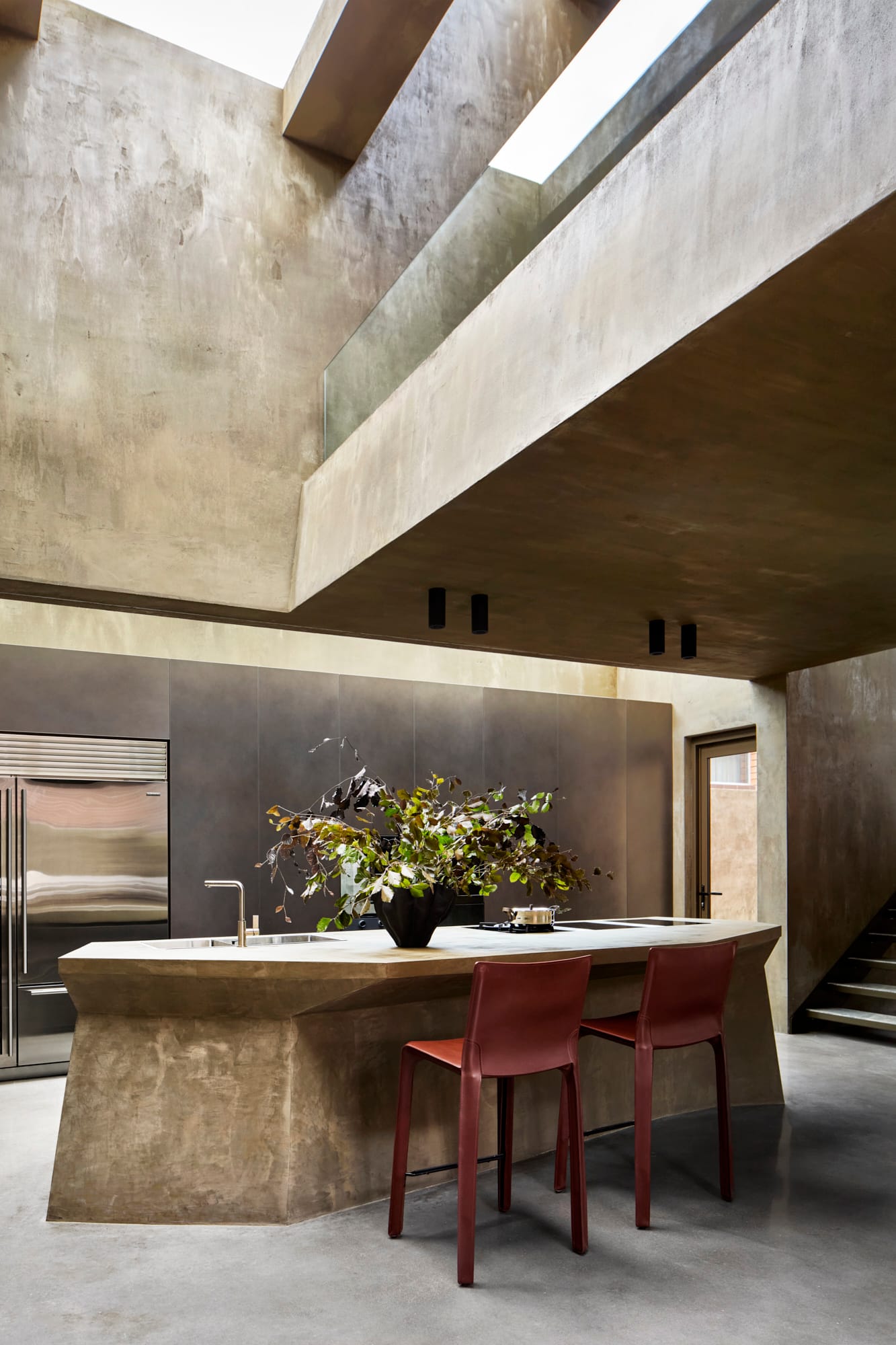 Proclamation House by State of Kin. Customised hempcrete kitchen island featuring sharp edges, skylight and brick colored bar stools.