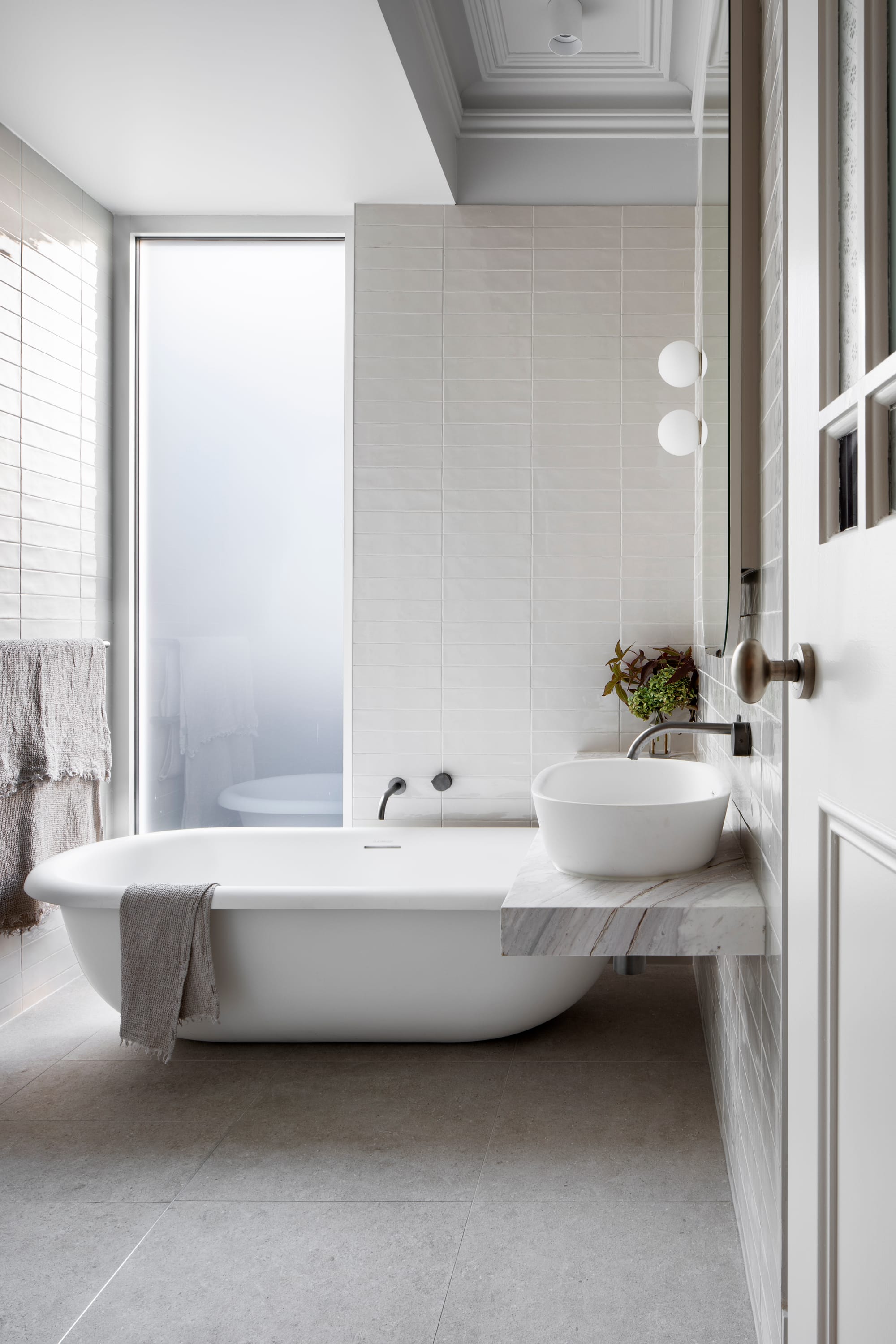 South Terrace Residence by Chan Architecture. Bathroom featuring free standing bathtub, marble fitting and grey squared floor tiled.