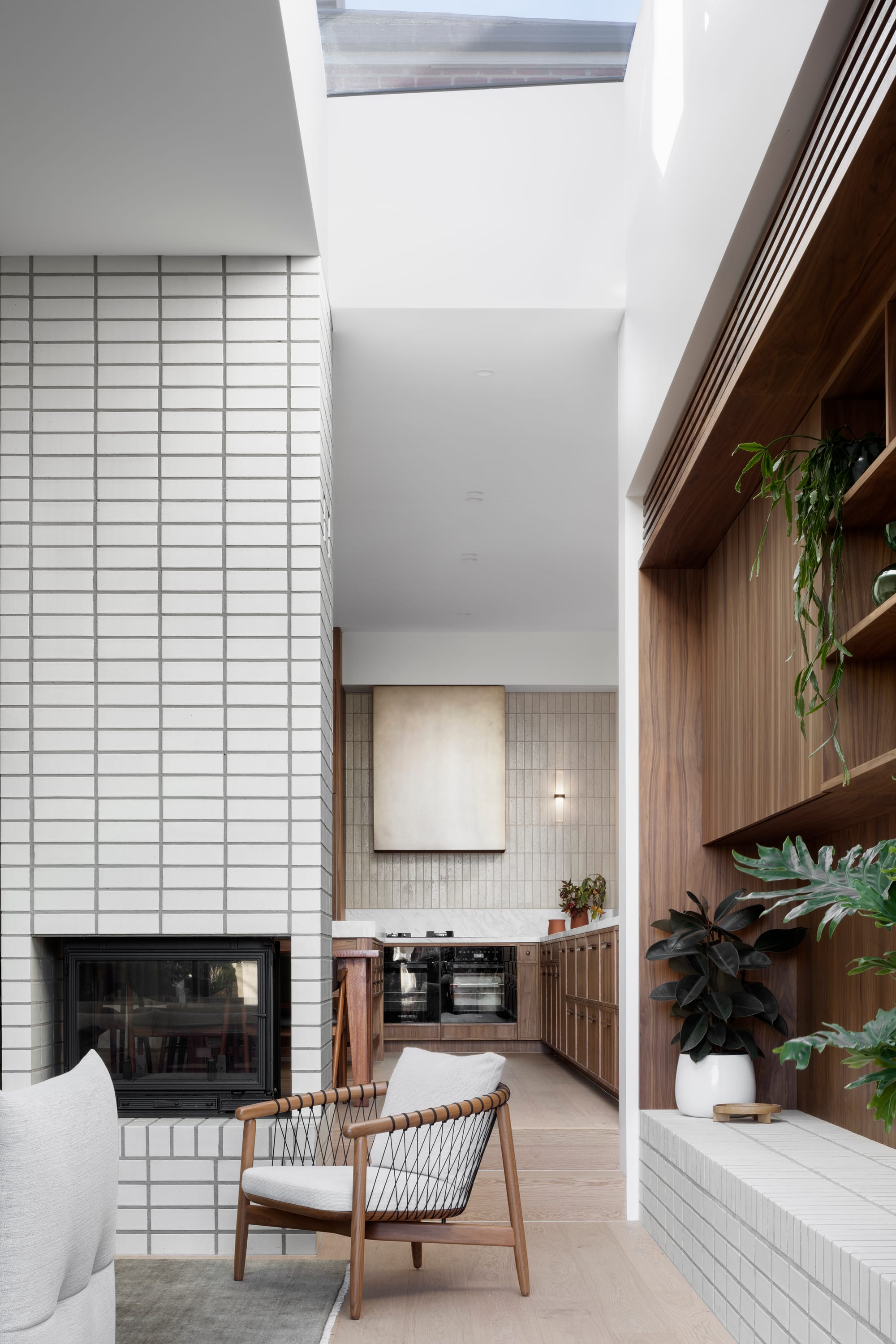 South Terrace Residence by Chan Architecture. Living space featuring white brick wall integrated chimney and view to kitchen.