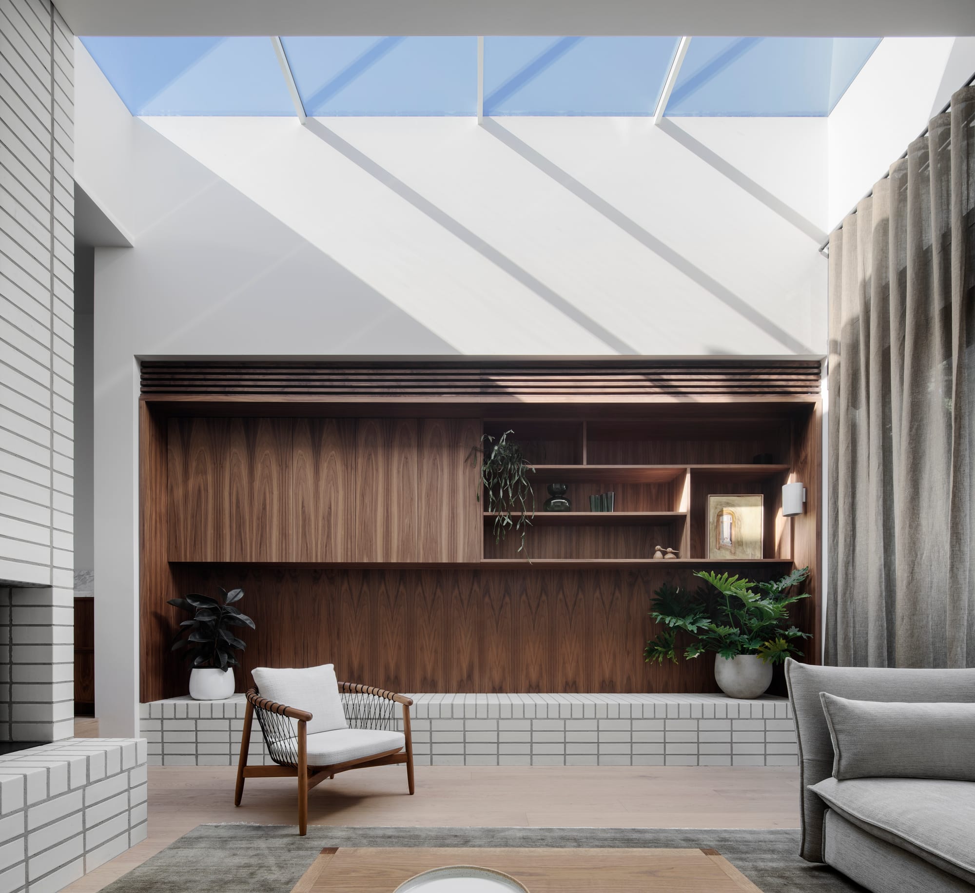 South Terrace Residence by Chan Architecture. Living space featuring integrated walnut wood shelving and skylight.