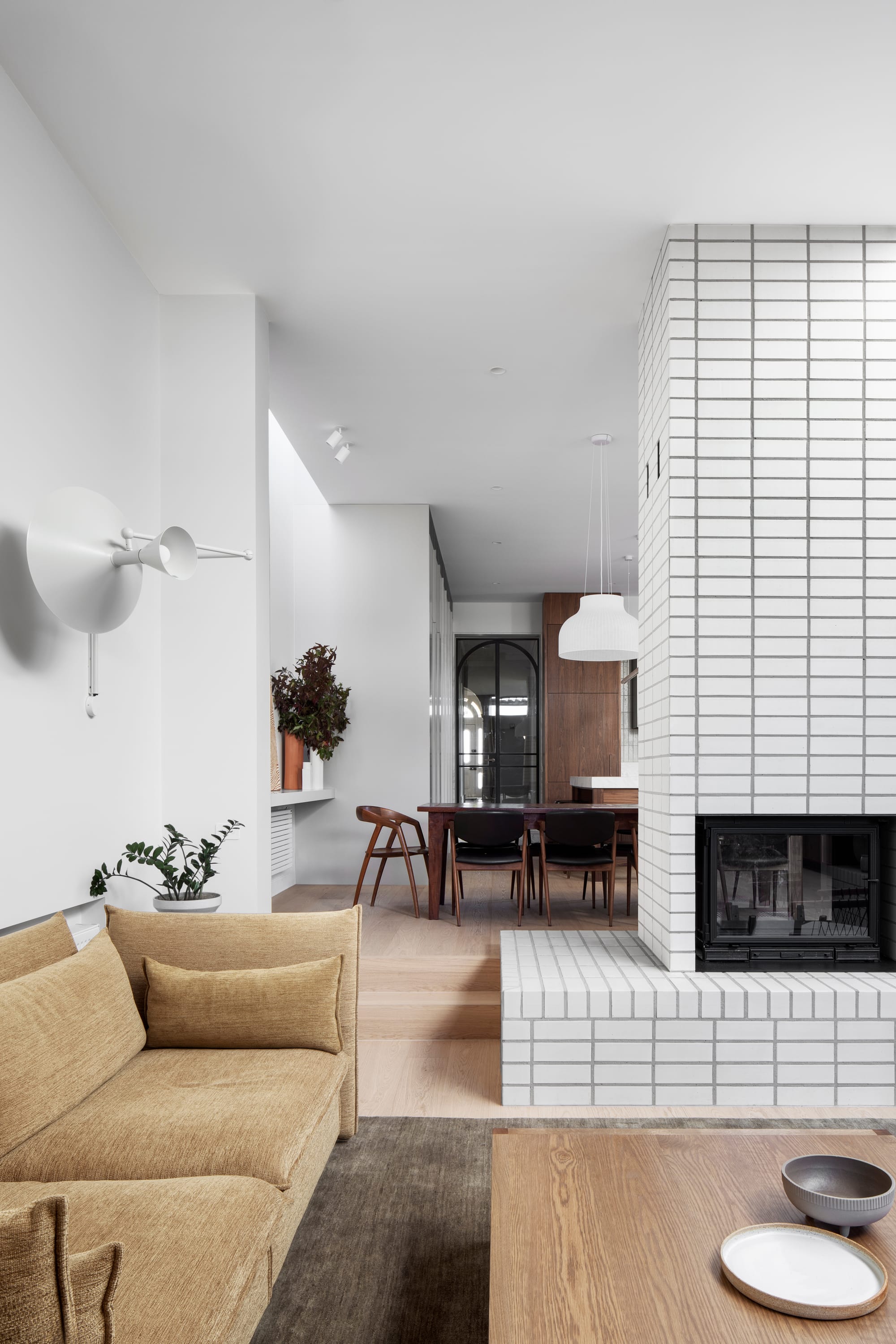 South Terrace Residence by Chan Architecture. Living space featuring white brick wall integrated chimney and view to dining.