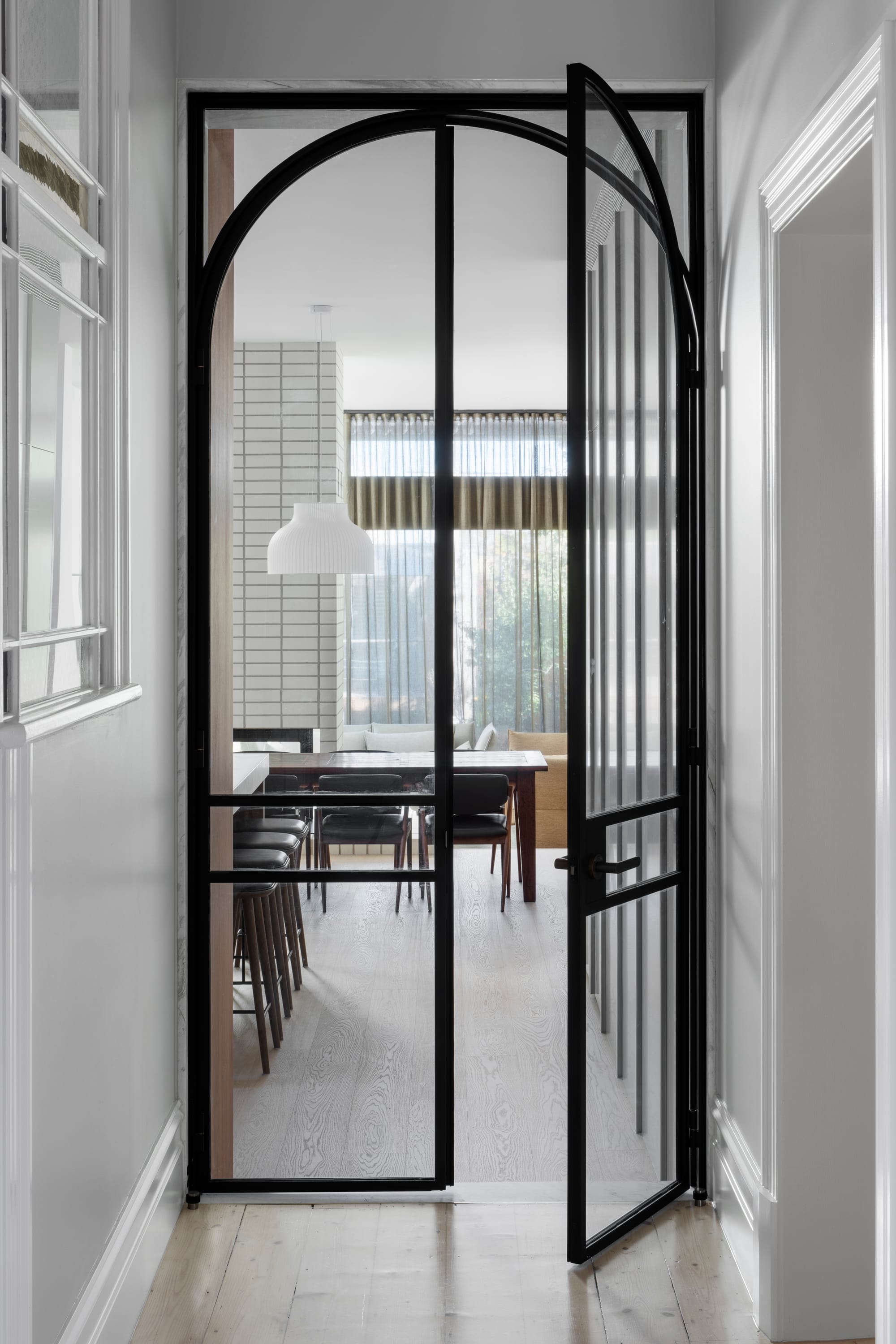 South Terrace Residence by Chan Architecture. Glas door featuring black steel arch frame and view to dining area. 