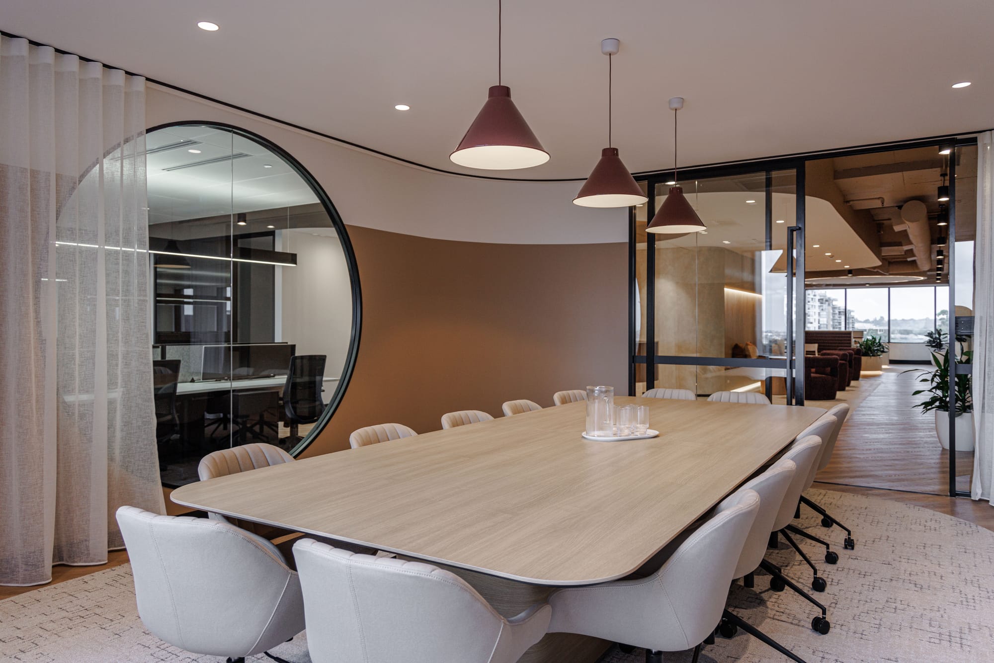 St Leonards Centuria Office Fit-Out by Alinea. View to customised, round reception desk and office lounge area featuring suspended ceiling.