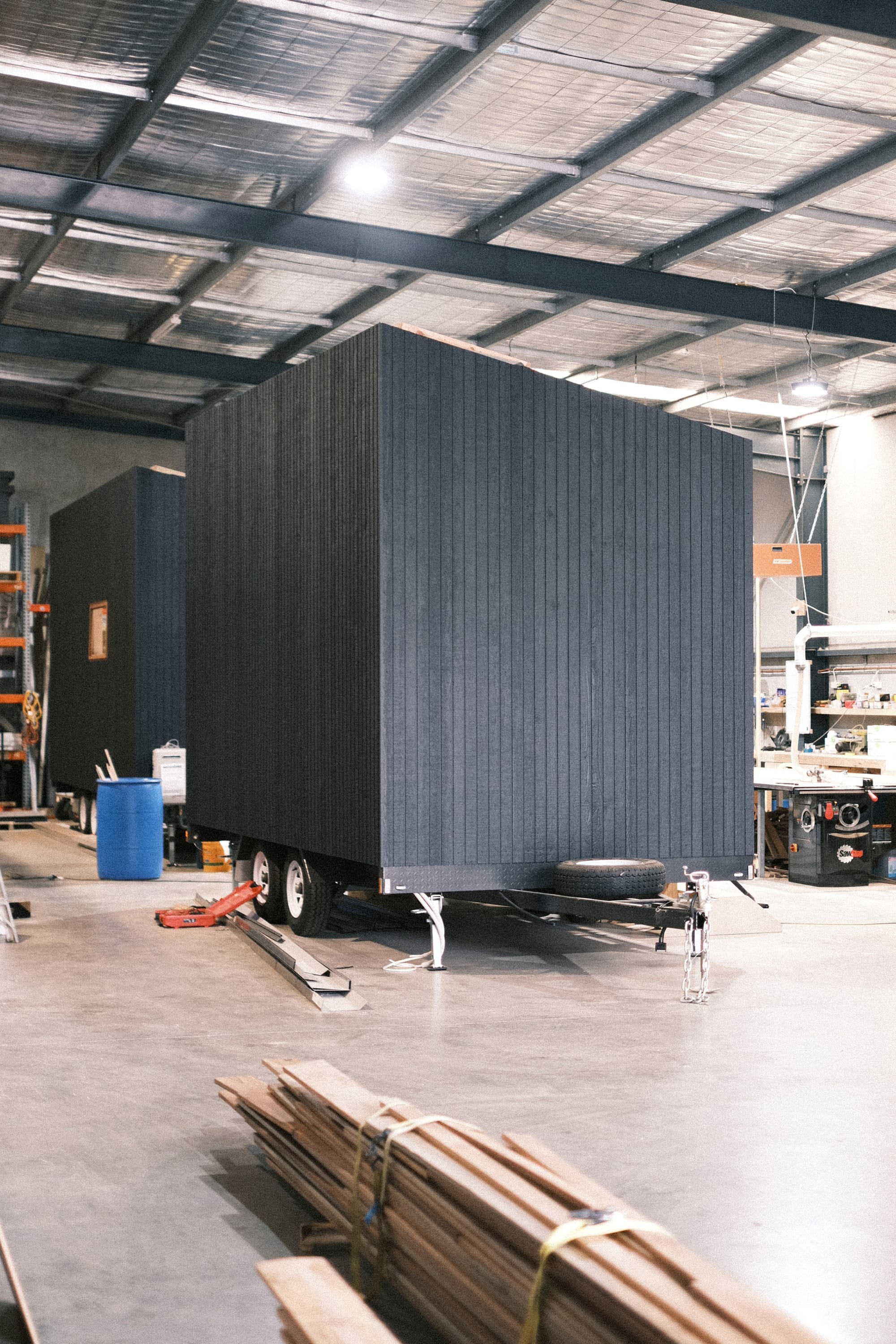 Workshop at Base Cabin. Workshop environment featuring tiny house with black wood panel facade on trailer.