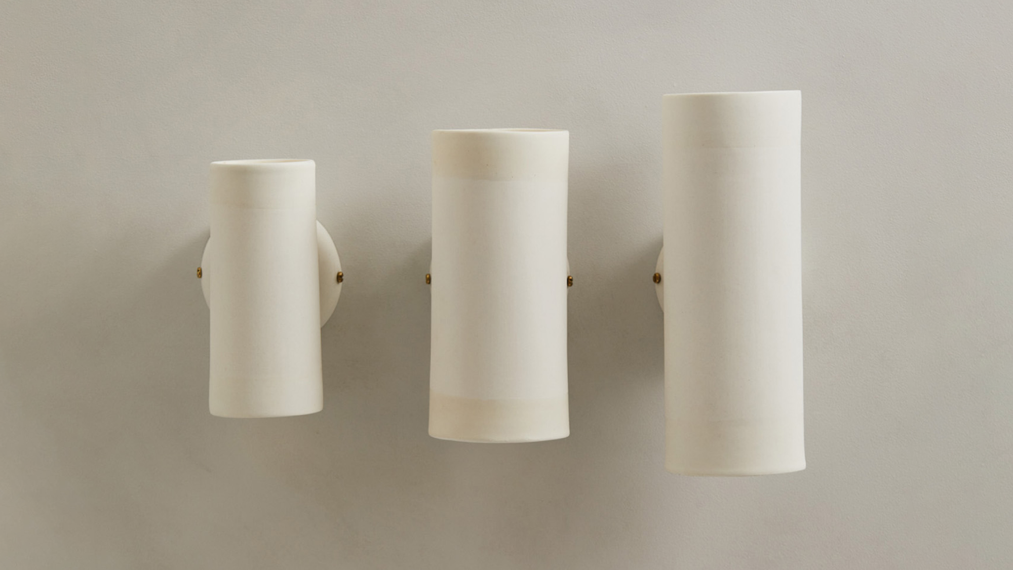 Dusked Eos Wall Light by Studio Etni with Lighterior. Three tube shaped white wall lights in different sizes.