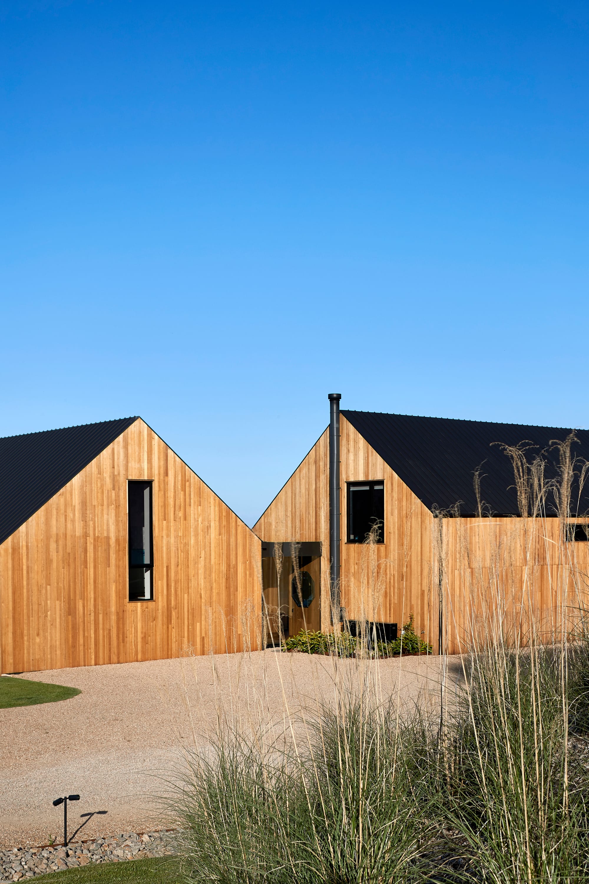 Flinders Residence by Abe McCarthy. Two modern houses, farmhouse charm featuring gabele roof and wood panel facade from Tasmanian Oak.