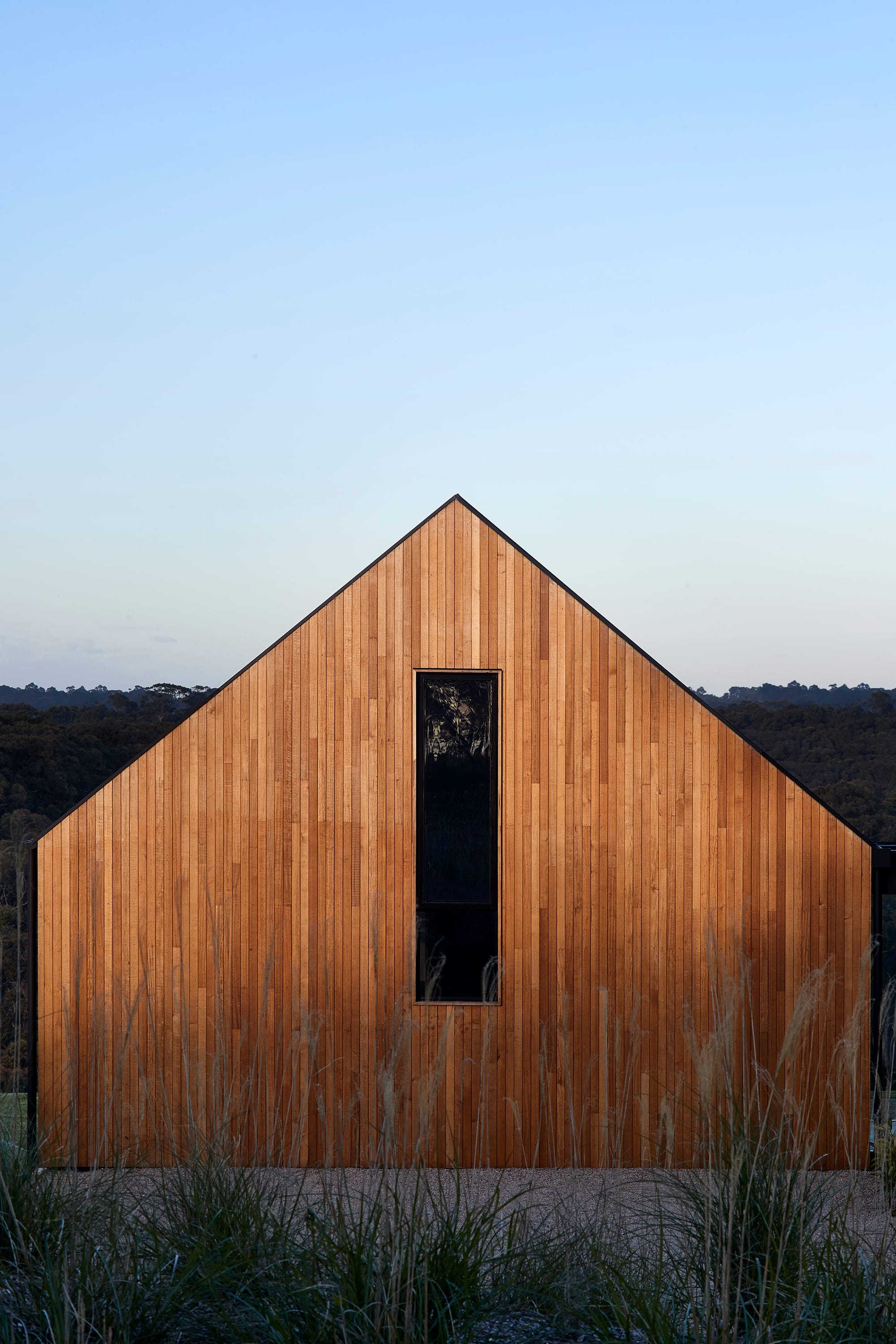 Flinders Residence by Abe McCarthy. Modern residence view featuring gable rood and Tasmanian oak wood panel facade surrounded by nature.