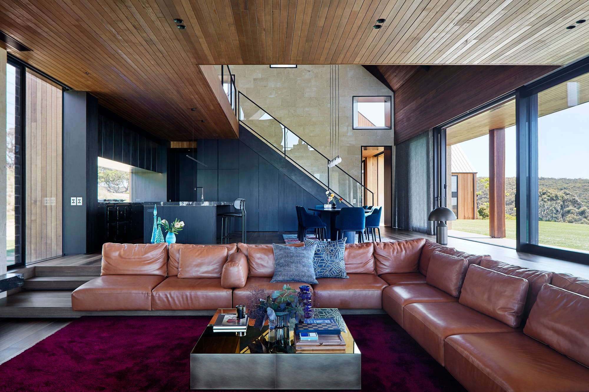 Flinders Residence by Abe McCarthy. Spacious contemporary open living room featuring bespoke cognac leather sofa, view to kitchen and garden.