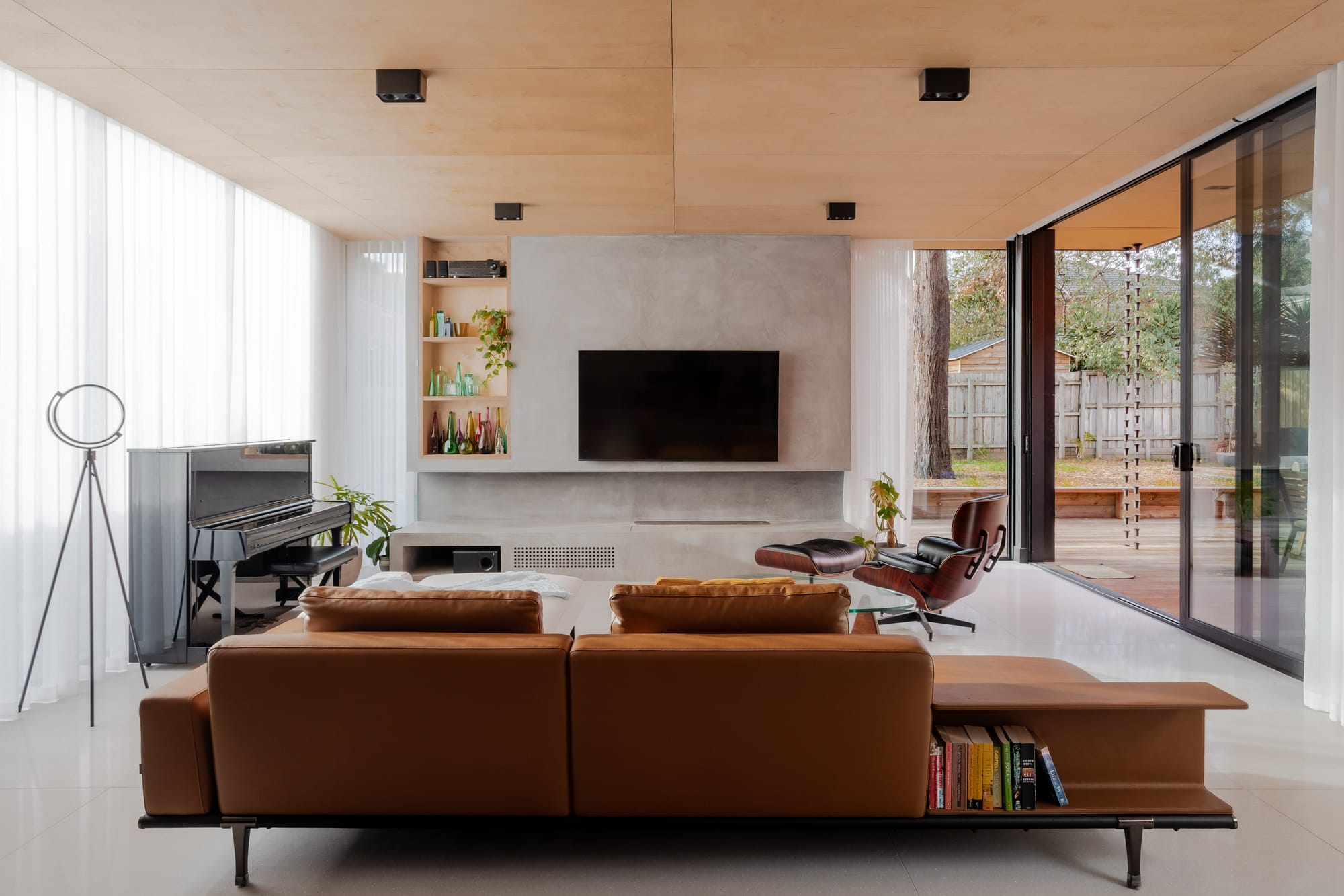 Mahogany House by R Architecture. Modern minimalistic living room featuring leather sofa, concrete walls and plywood ceiling.