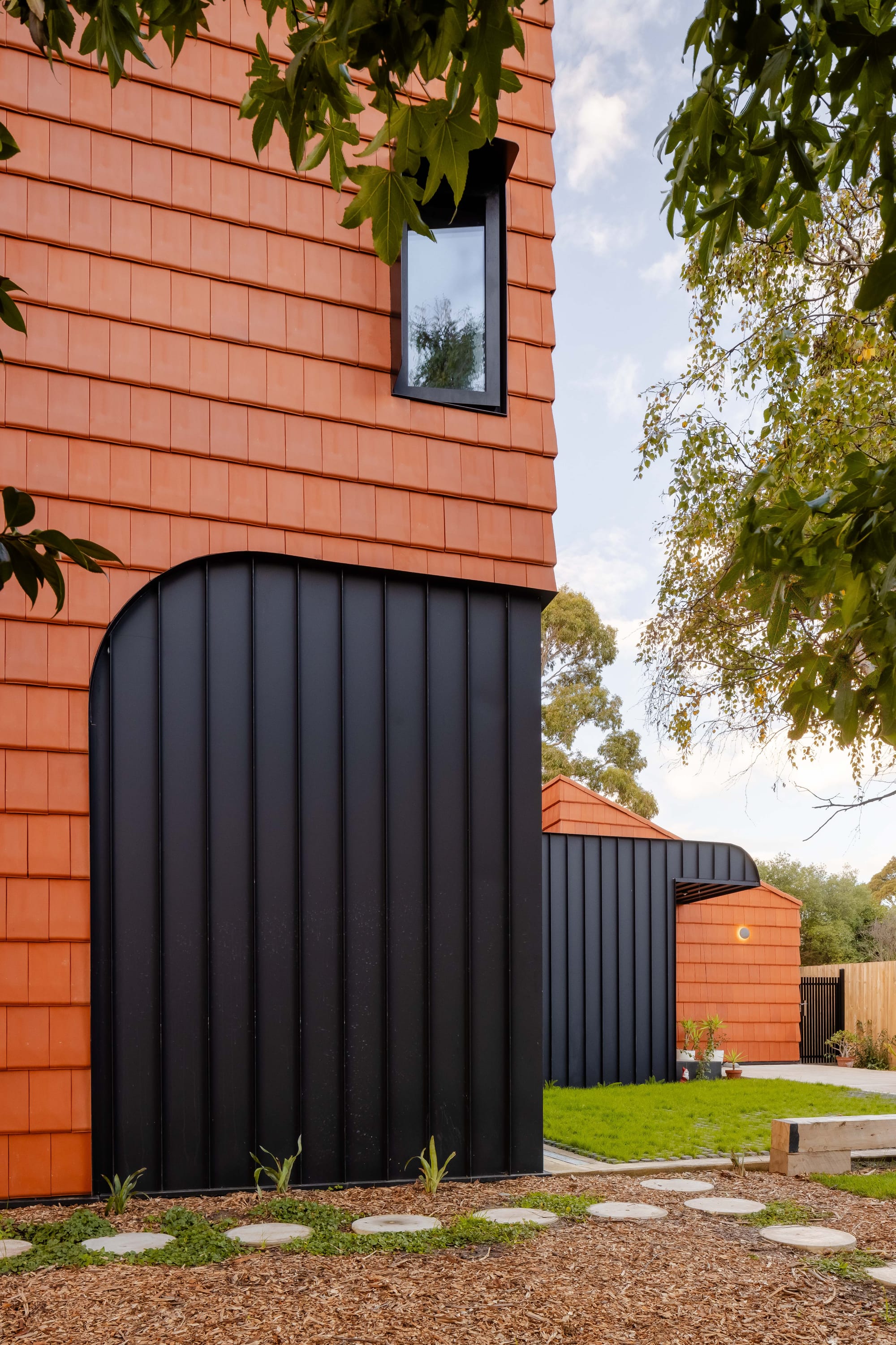 Mahogany House by R Architecture. Terracotta shingle Facade featuring black powder coated arch elements.