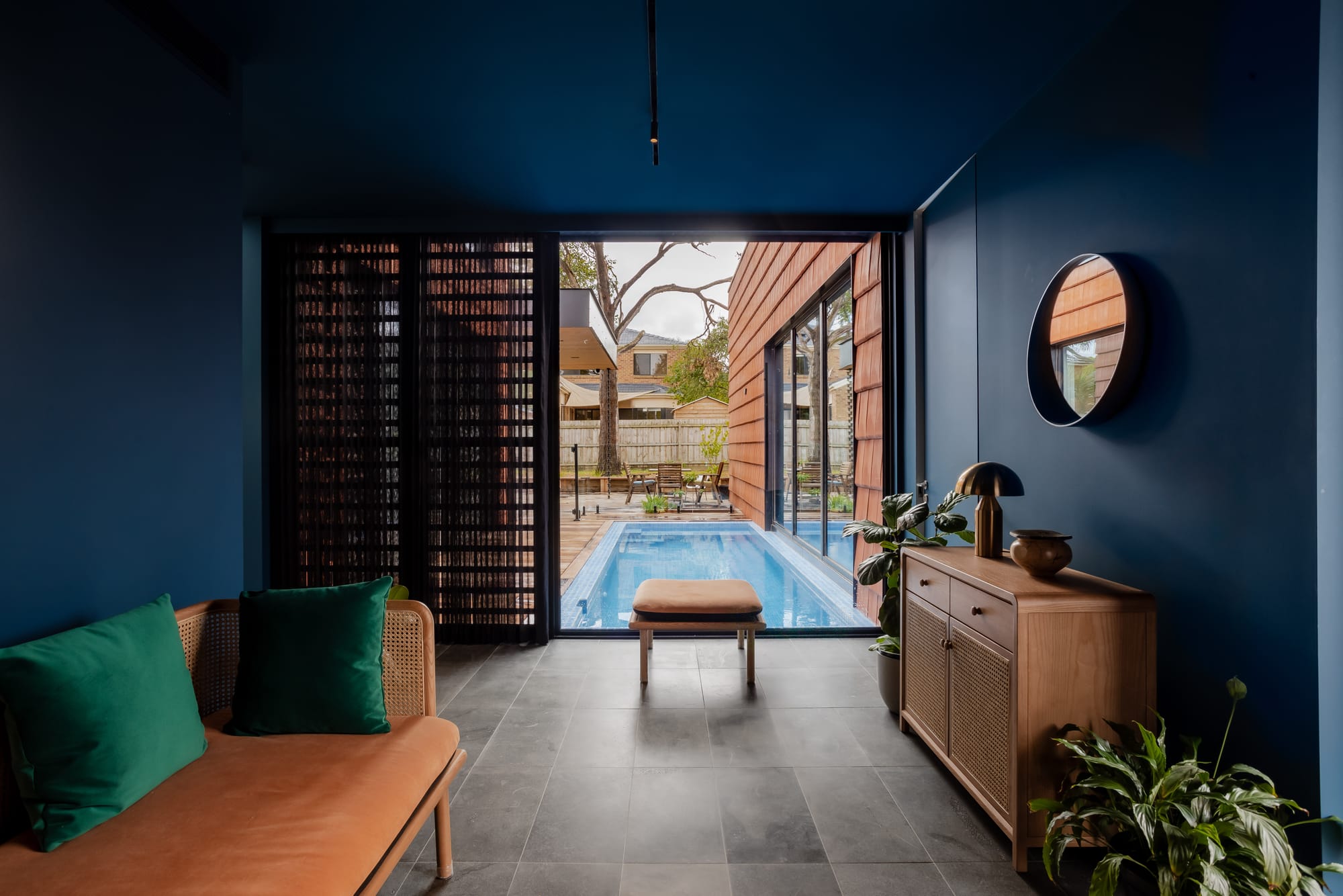 Mahogany House by R Architecture. Interior space featuring petrol colored walls and ceiling with view to pool and courtyard.